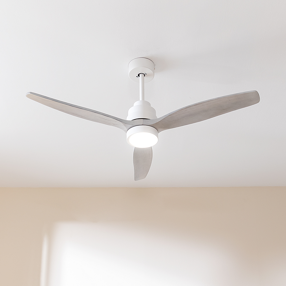 Ventilador de techo moderno con tres aspas de madera y luz integrada en un techo blanco.