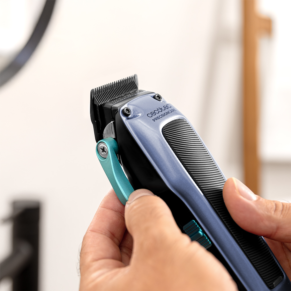 Manos sosteniendo una maquinilla de cortar pelo azul de Cecotec con cuchillas negras y palanca azul clara.