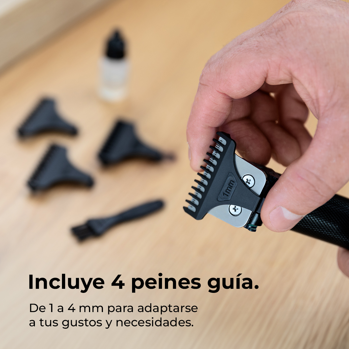 Mano sosteniendo cabezal de cortapelos con peine, accesorios y aceite en mesa.
