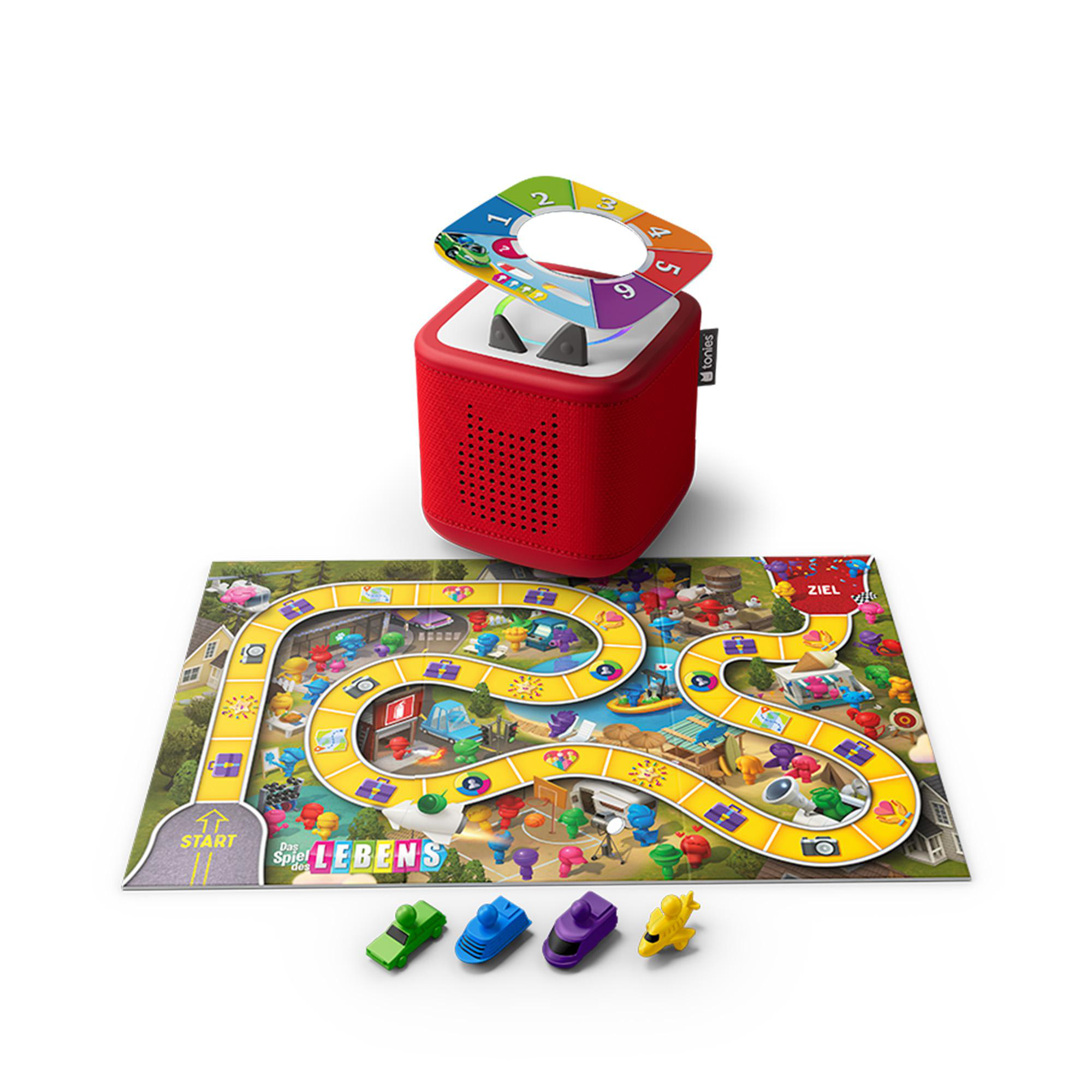 Ein roter Toniebox-Lautsprecher steht über einem farbenfrohen Das Spiel des Lebens-Brettspiel mit kleinen Autos.