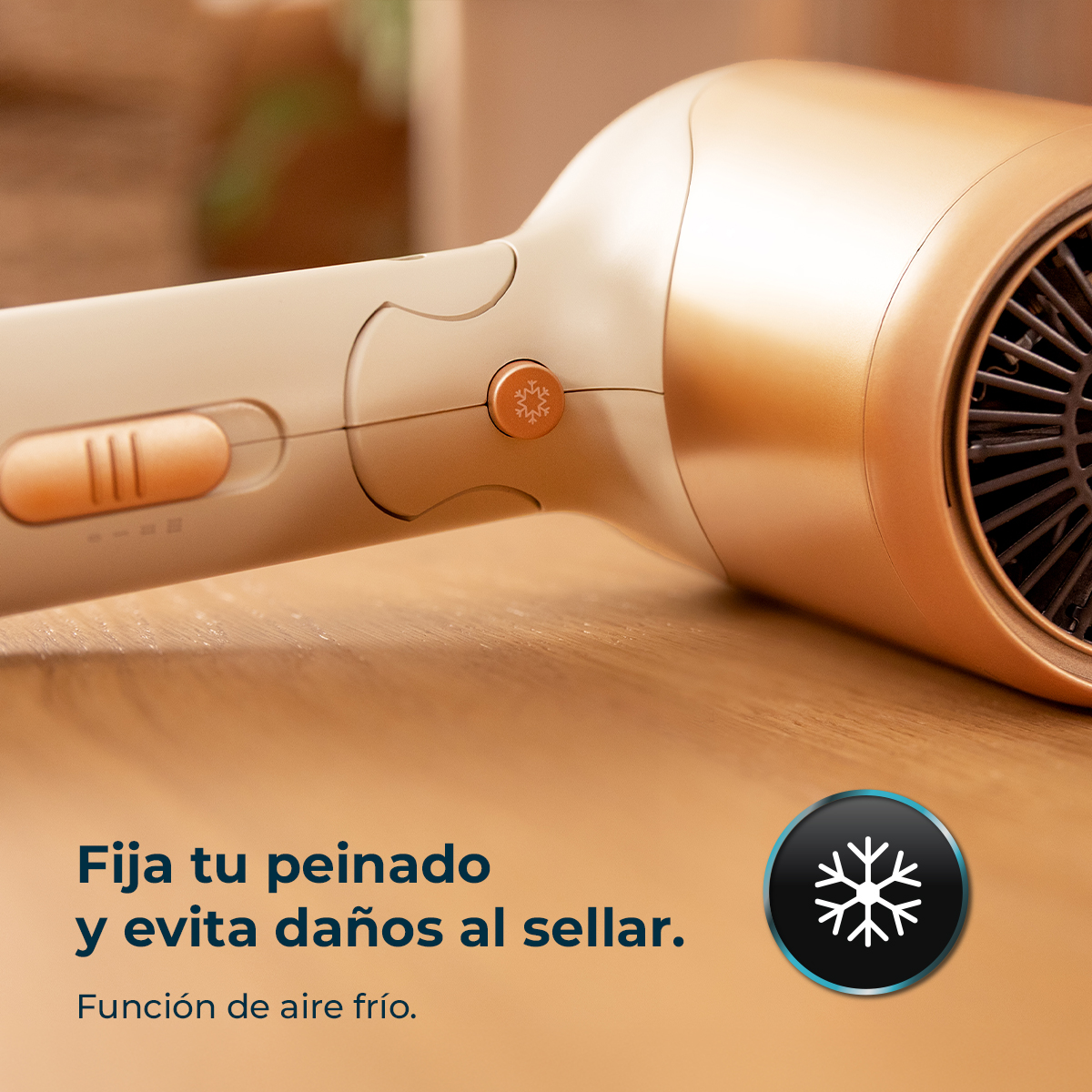 Secador de pelo dorado sobre superficie de madera con función de aire frío y texto en español.