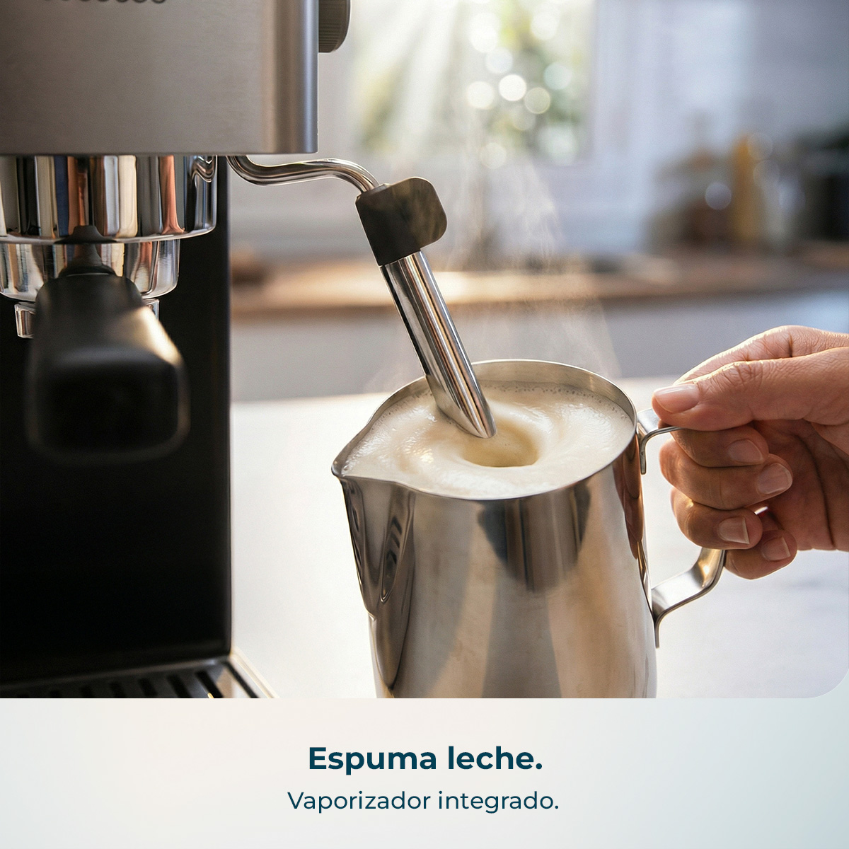 Una mano sostiene una jarra de leche mientras el vaporizador de una cafetera espuma la leche.