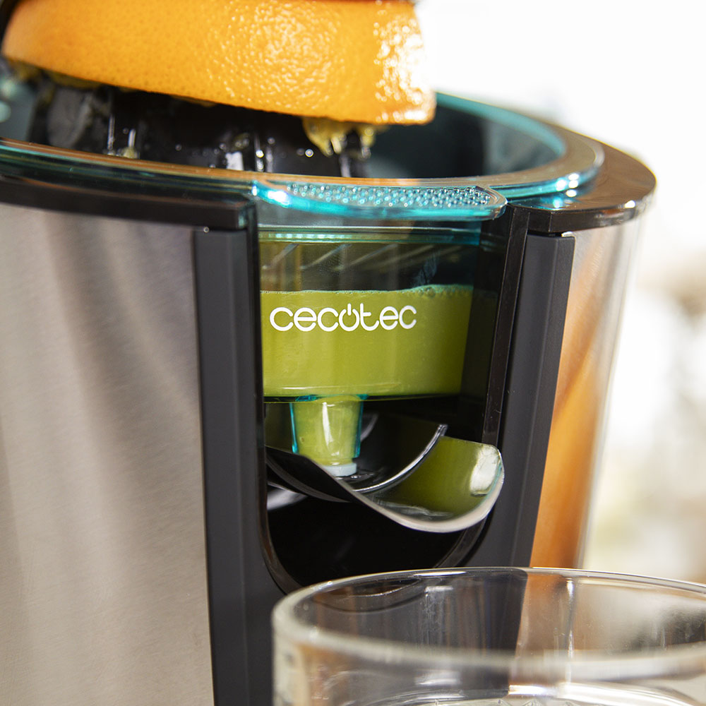 Un exprimidor Cecotec extrae zumo de naranja fresco que se acumula en un depósito.