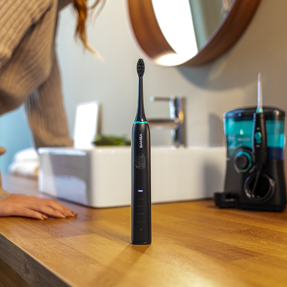 Un cepillo de dientes eléctrico negro sobre un mostrador de madera en un baño moderno.