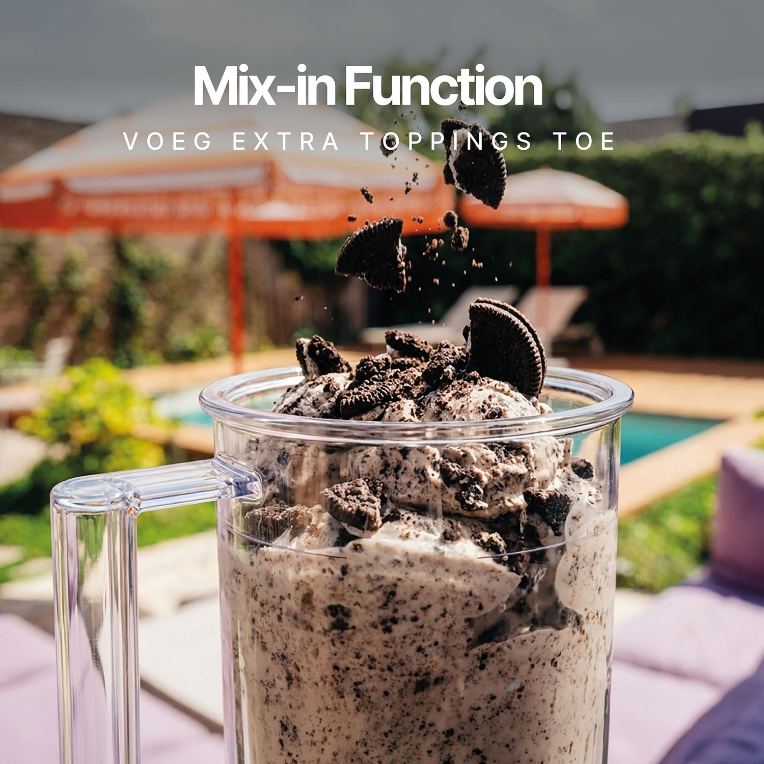 Cookies and cream ice cream in a blender with cookie pieces falling in, outdoors by a pool.