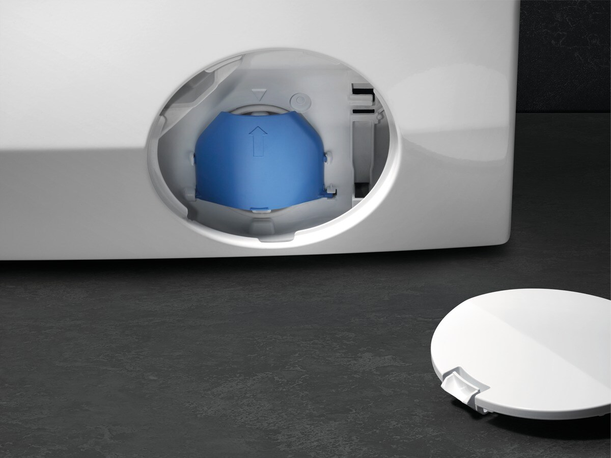 La trampilla de mantenimiento abierta de una lavadora con un filtro azul y la tapa redonda blanca retirada.
