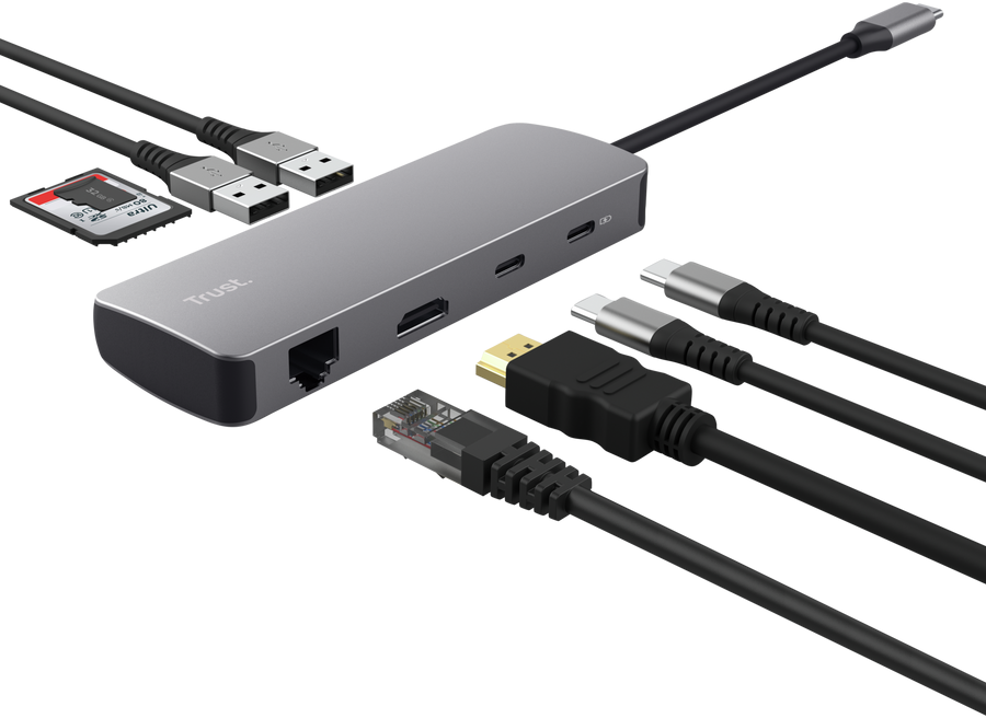 Grauer Trust USB-C Hub mit verschiedenen angeschlossenen Kabeln und einer SD-Karte auf schwarzem Hintergrund.