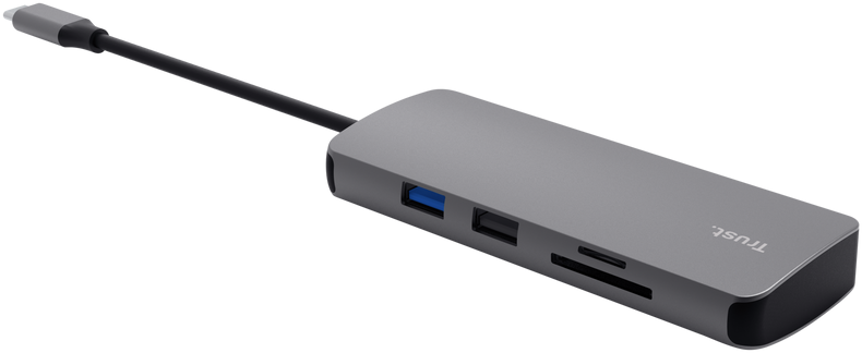 Ein grauer Trust USB-C Hub mit mehreren Anschlüssen und einem angeschlossenen Kabel auf schwarzem Hintergrund.