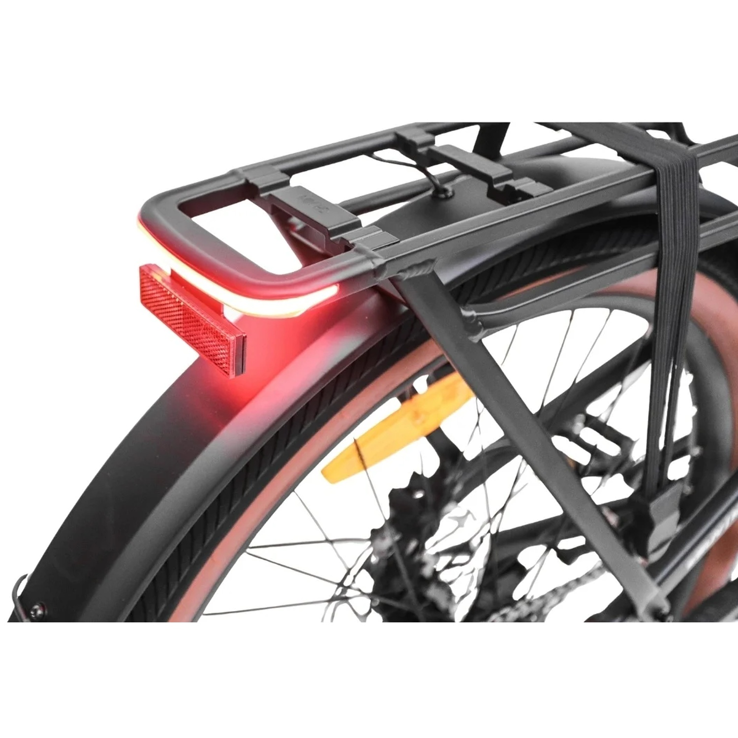 Gros plan sur le porte-bagages arrière d'un vélo, avec un feu rouge éclairé et un réflecteur.