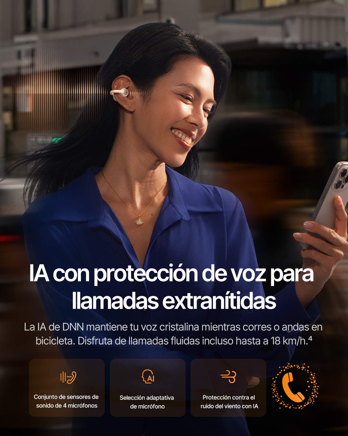 Una mujer sonriente con camisa azul lleva auriculares inalámbricos y sostiene un smartphone.