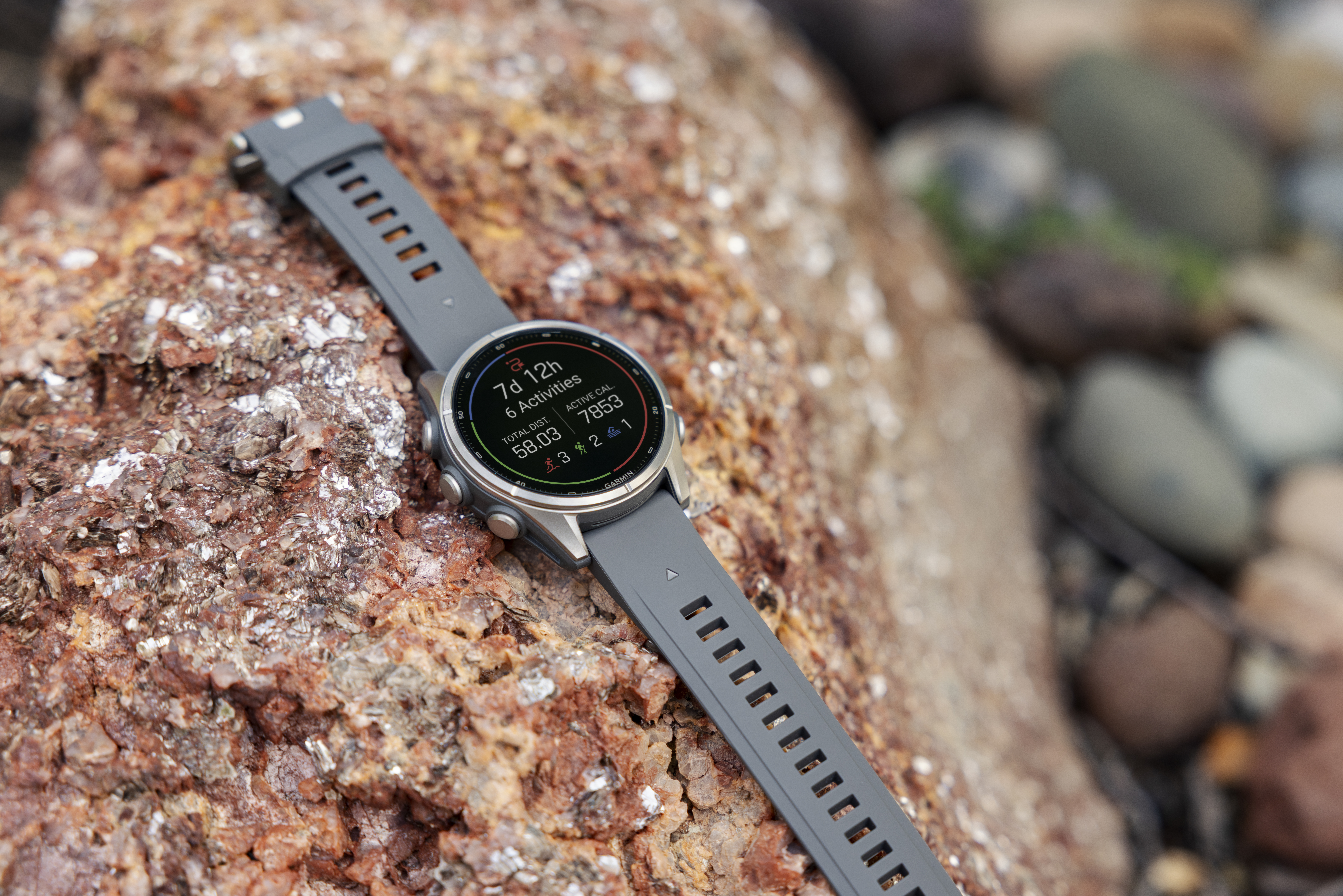 Eine graue Sportuhr mit digitalem Display liegt auf einem rötlichen Felsen.