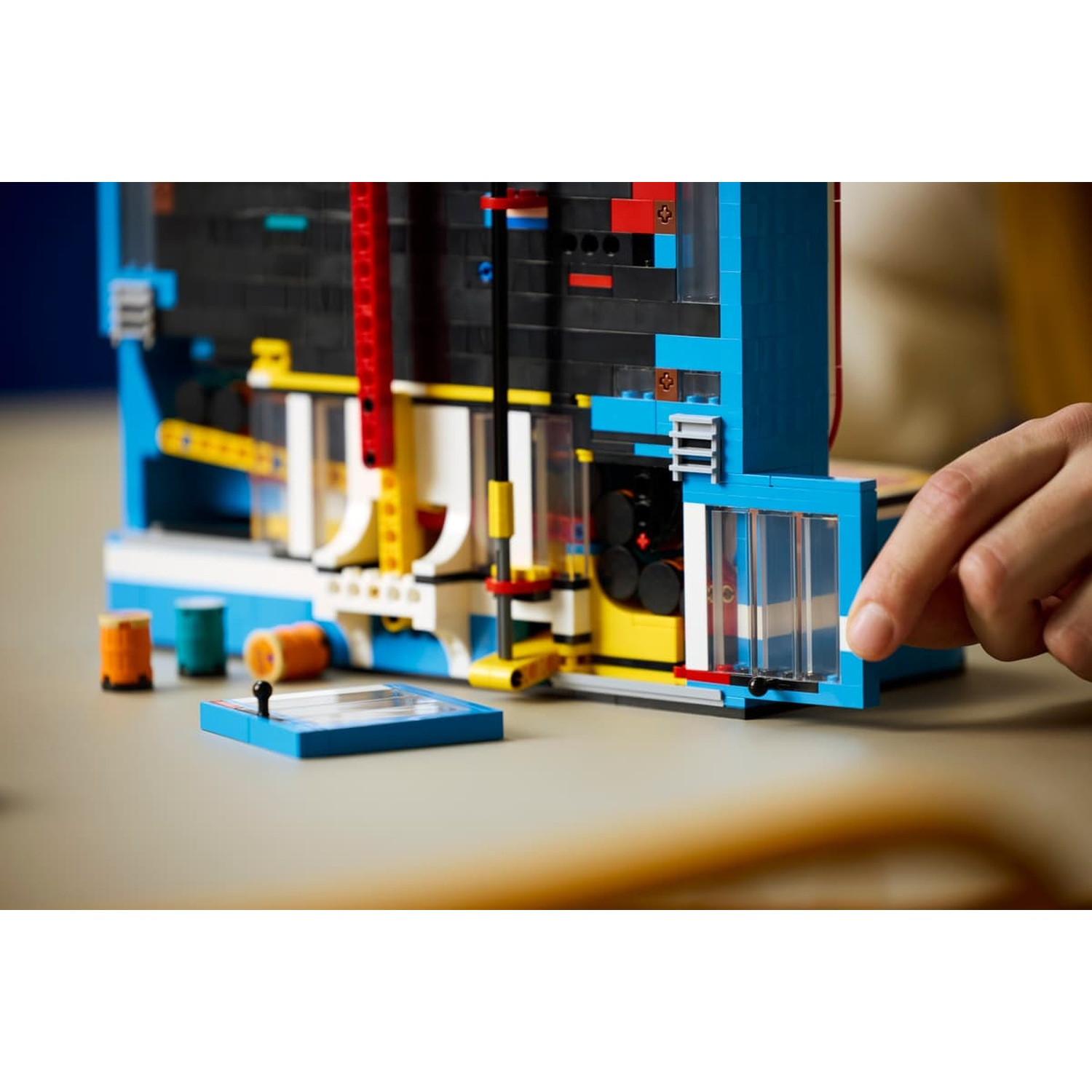 Una mano apre la porta di un modello Lego blu e nero su un tavolo.