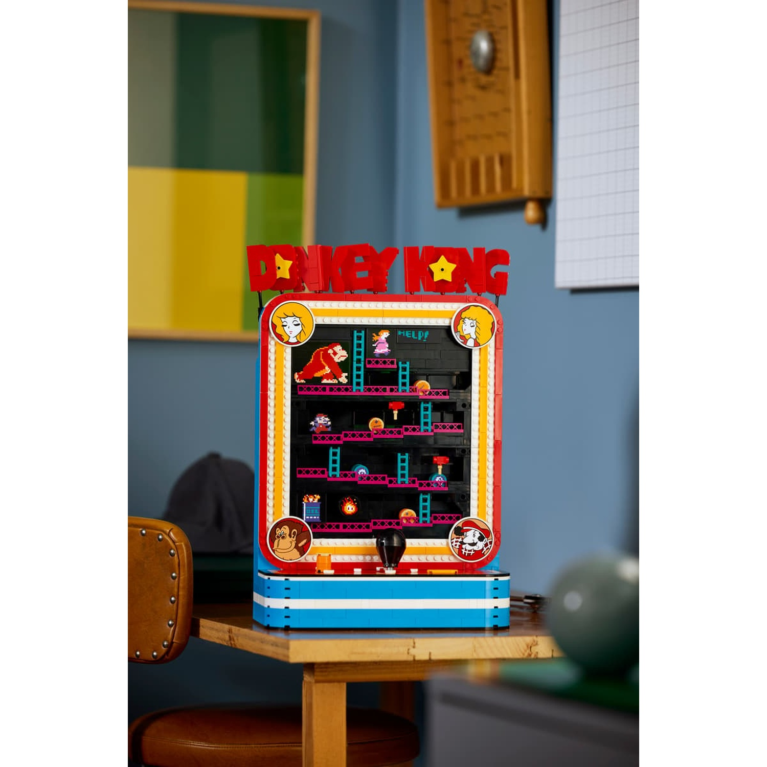 Un cabinato arcade Lego Donkey Kong si trova su una scrivania di legno davanti a una parete blu.