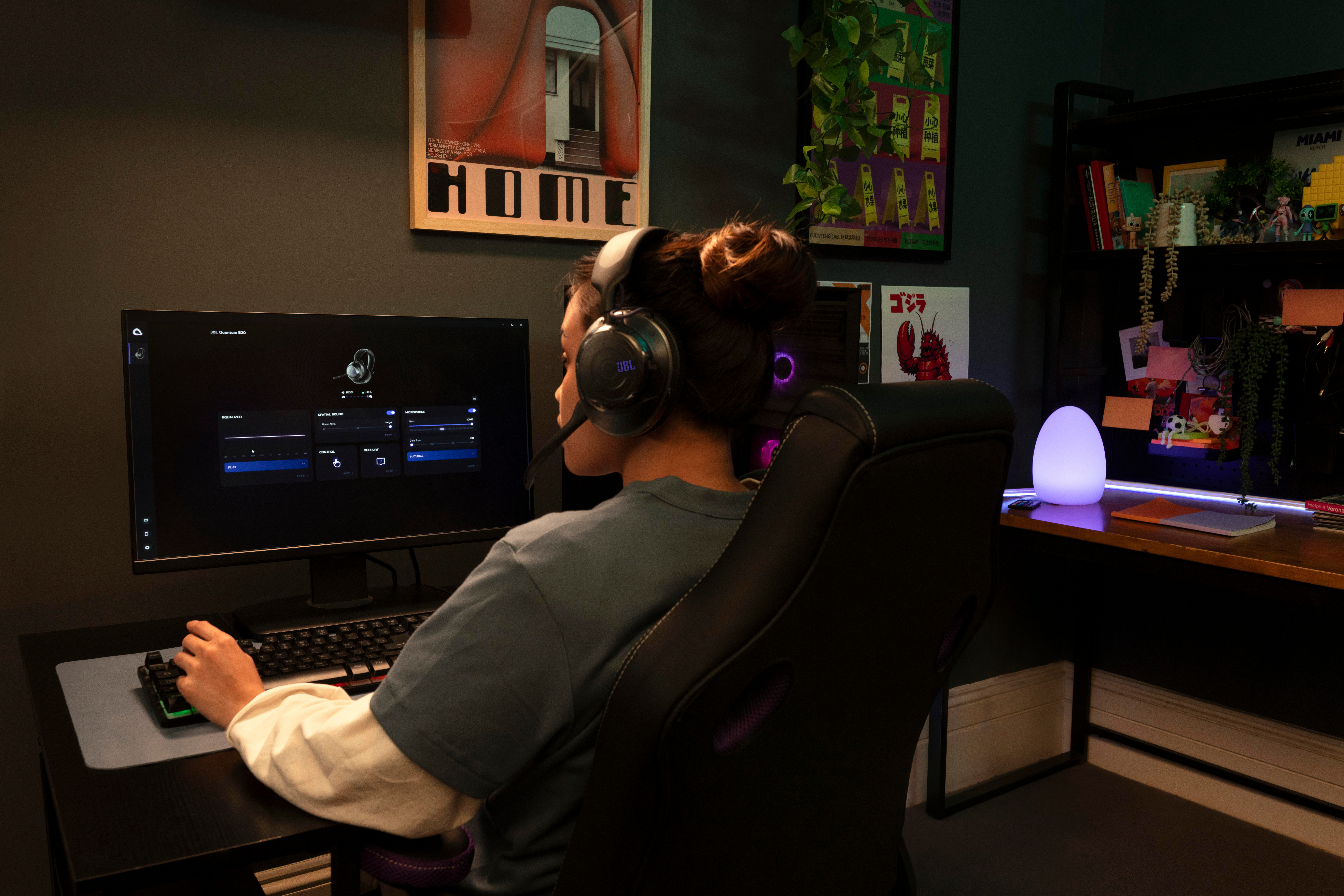 Eine Person mit Headset sitzt vor einem PC-Bildschirm und spielt in einem dunklen Zimmer.