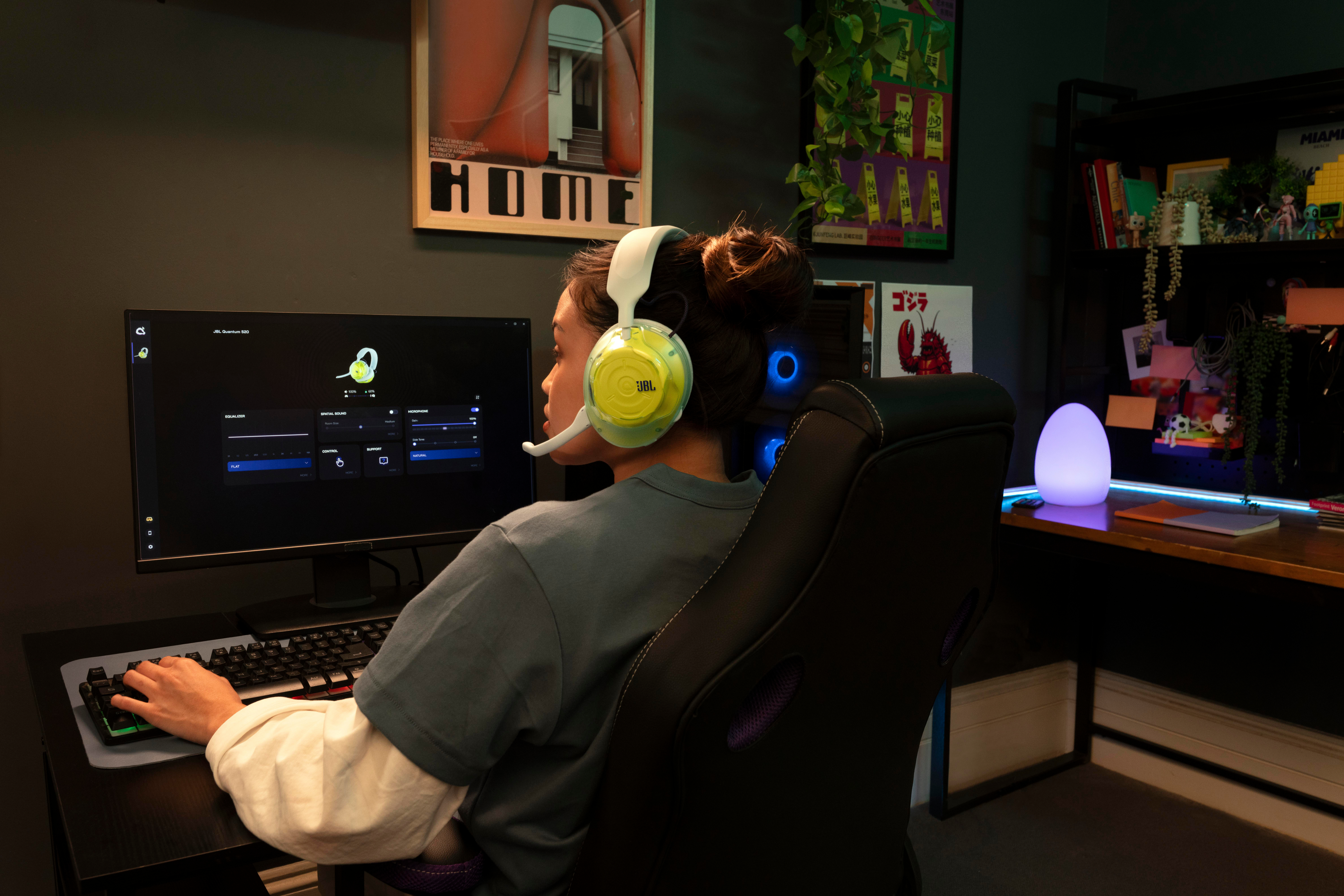 Eine Person mit Headset sitzt vor einem Computer und spielt in einem dunklen Zimmer.