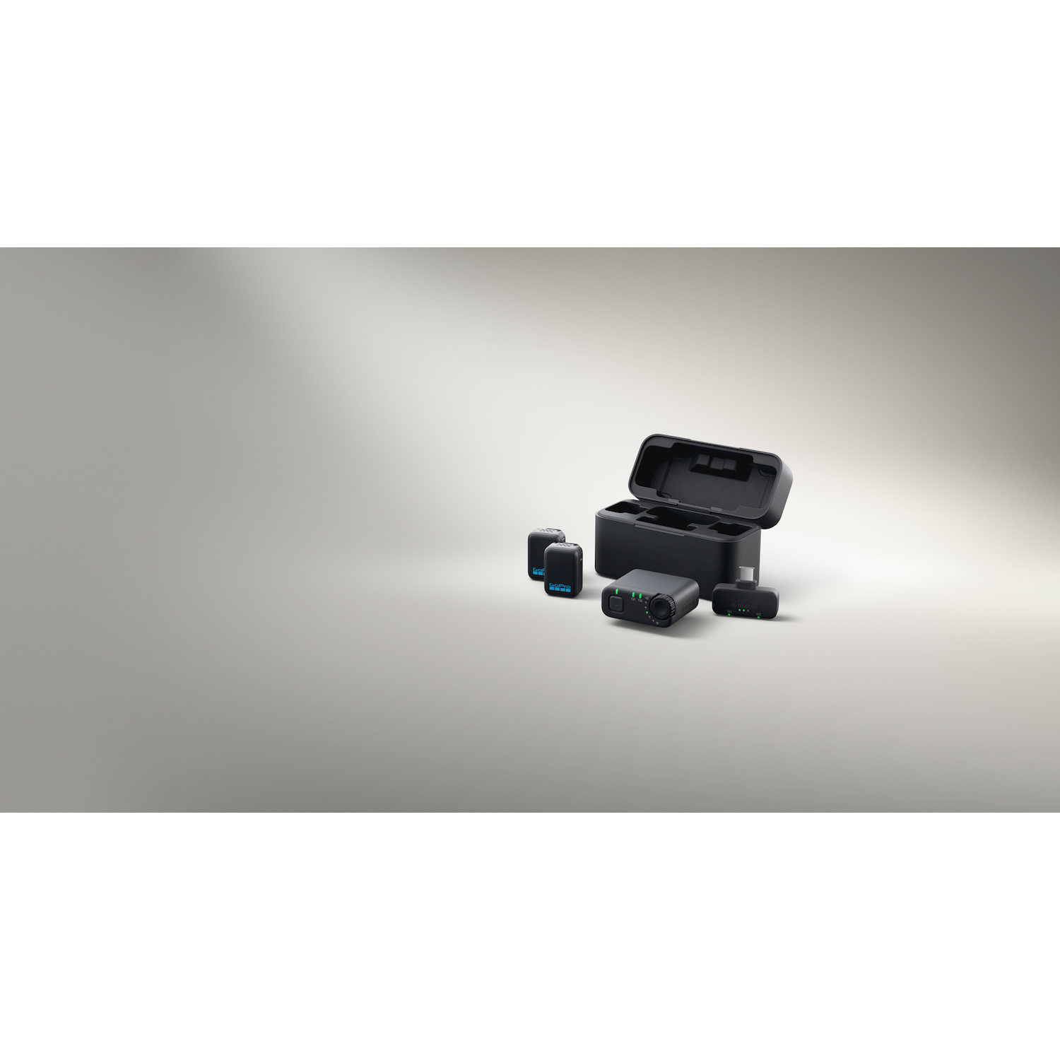 Kit audio GoPro nero con custodia di carica, due trasmettitori, un ricevitore e accessori su sfondo chiaro.