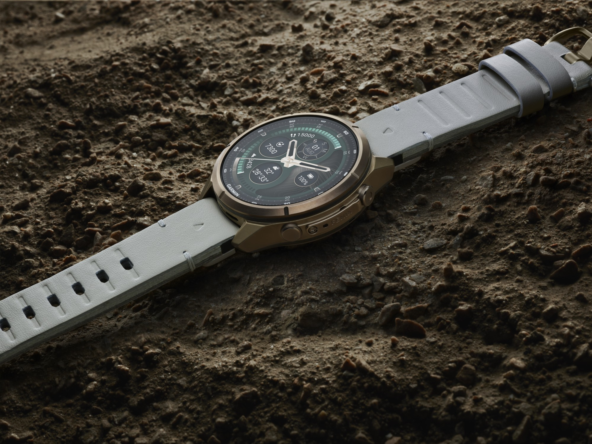 Brązowo-szary smartwatch leży na kamienistym podłożu.