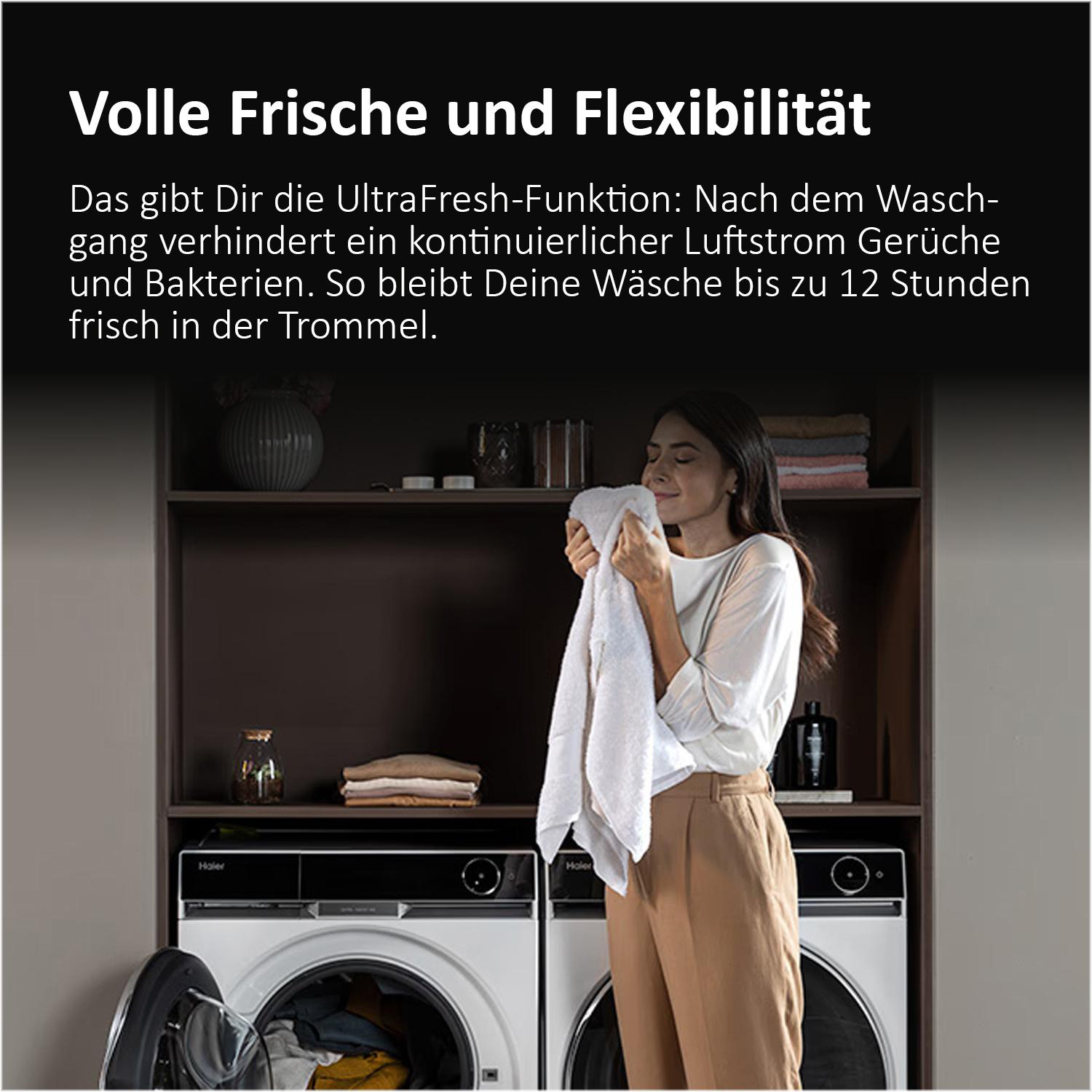 Eine Frau riecht an einem frisch gewaschenen Handtuch vor zwei Waschmaschinen und einem Regal mit Text und Logo.