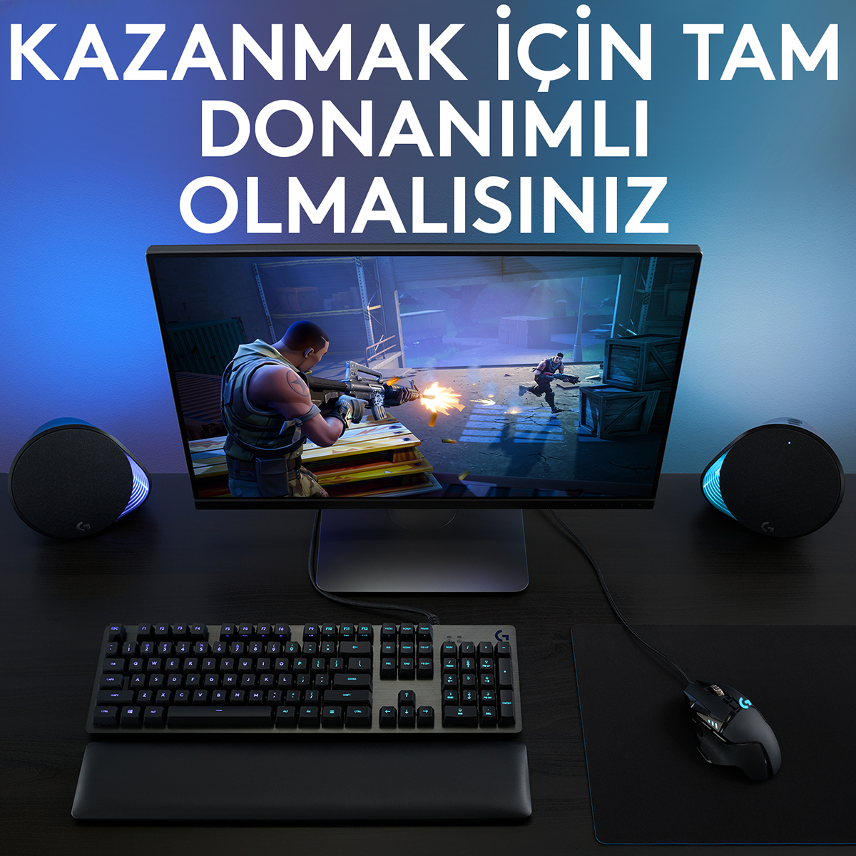 Mavi aydınlatmalı bir arka plan önünde monitör, klavye, fare ve hoparlörlerden oluşan bir oyun kurulumu.