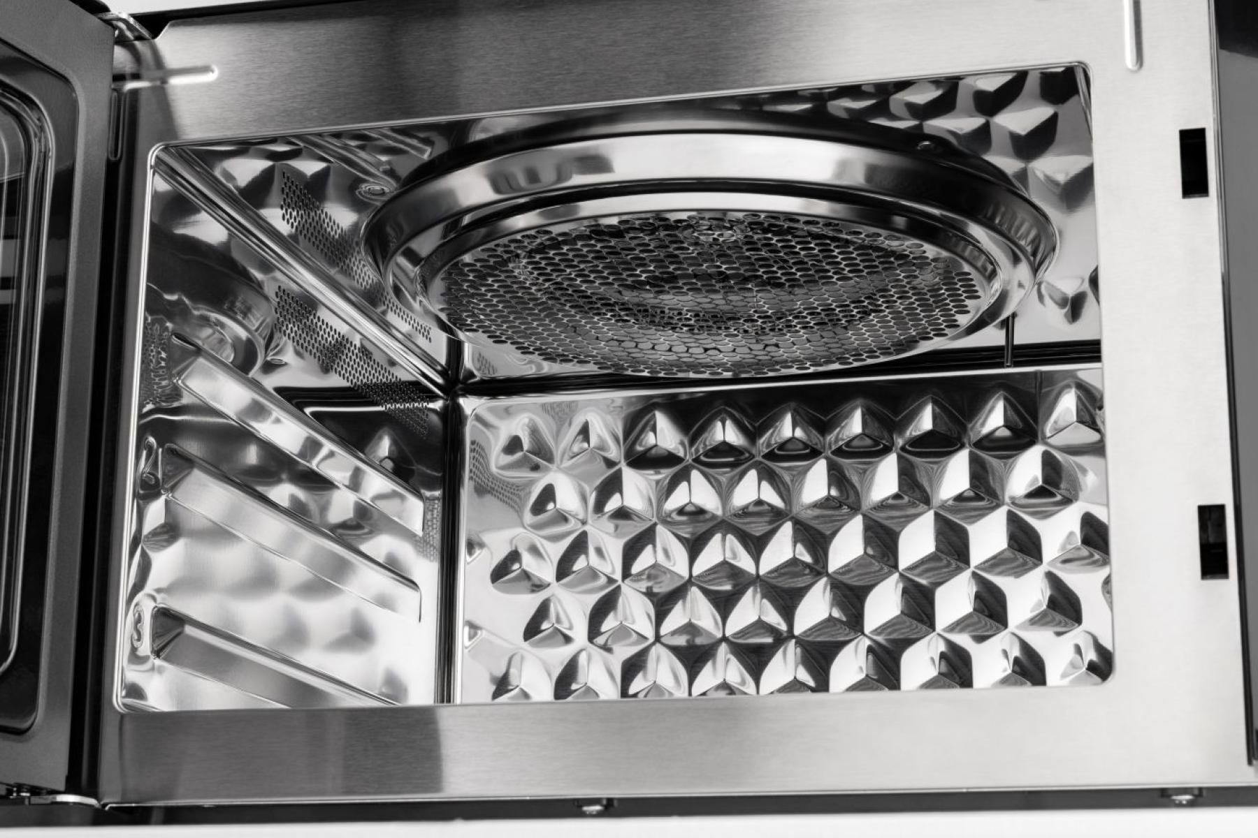 Das Innere einer Mikrowelle aus Edelstahl mit gepraegter Rueckwand und einer runden Grillplatte an der Decke.