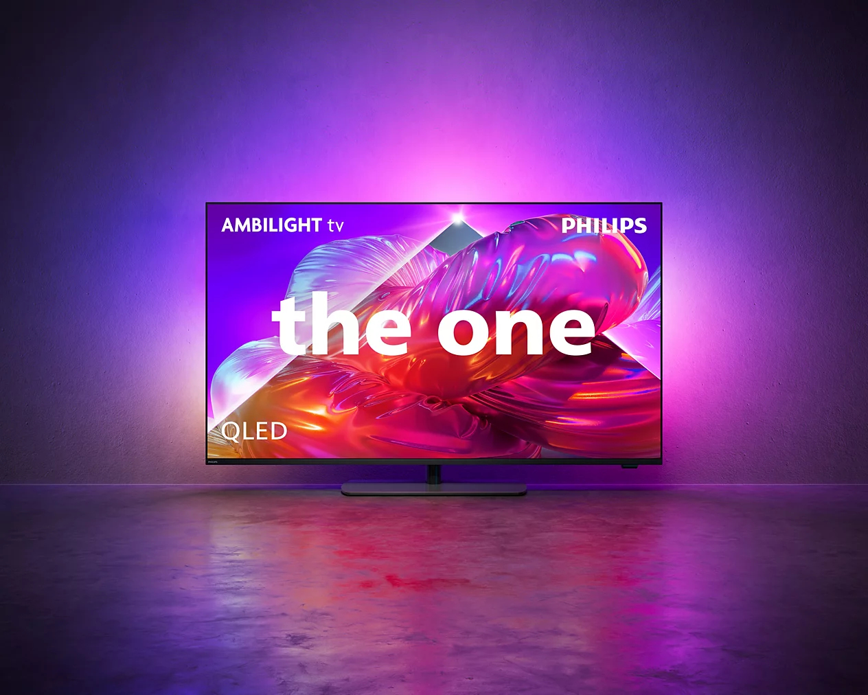 Telewizor Philips Ambilight QLED stoi na podłodze pod fioletową ścianą, emitując kolorowe światło.