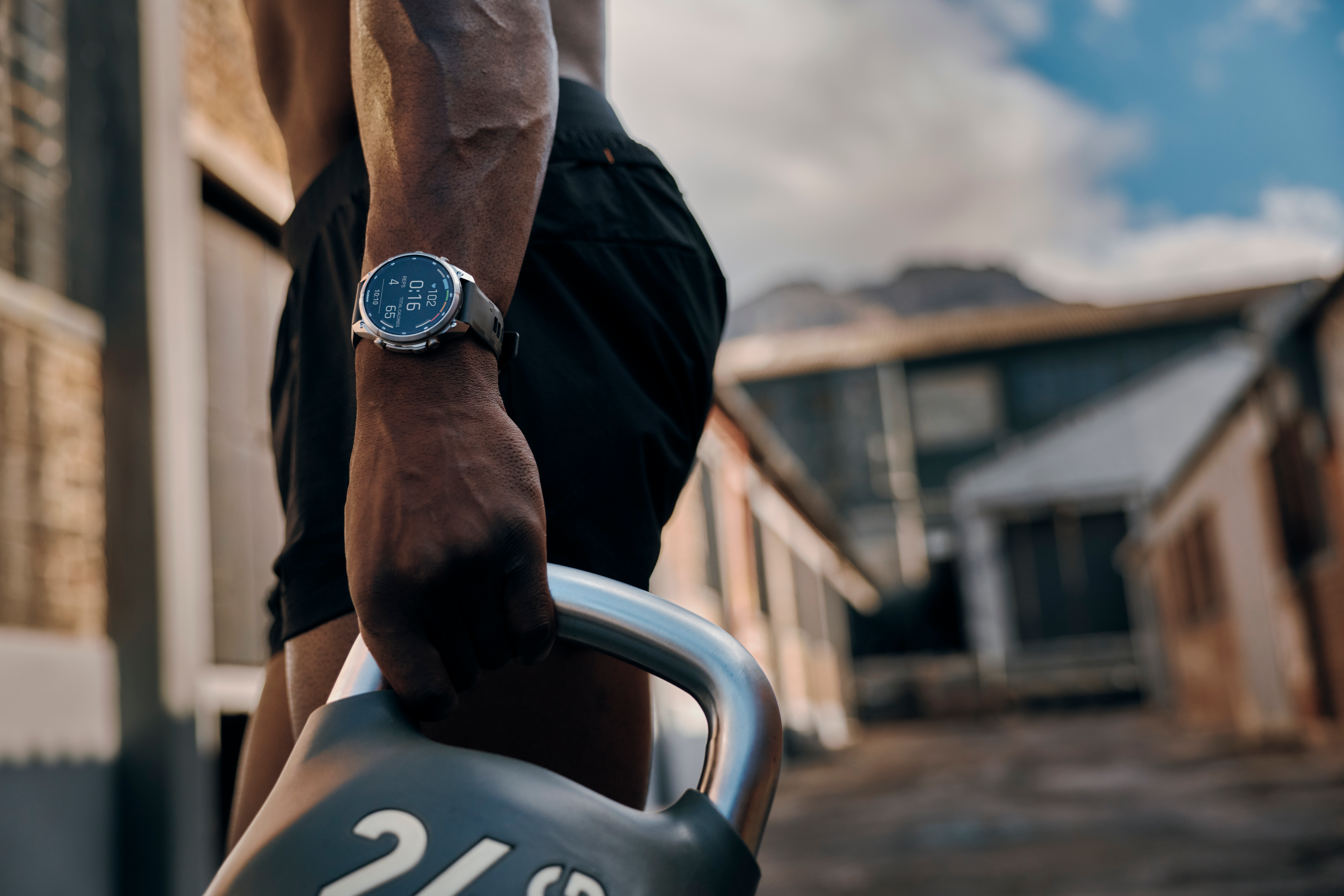 Ein Sportler hält eine Hantel und trägt eine Fitnessuhr im Freien.