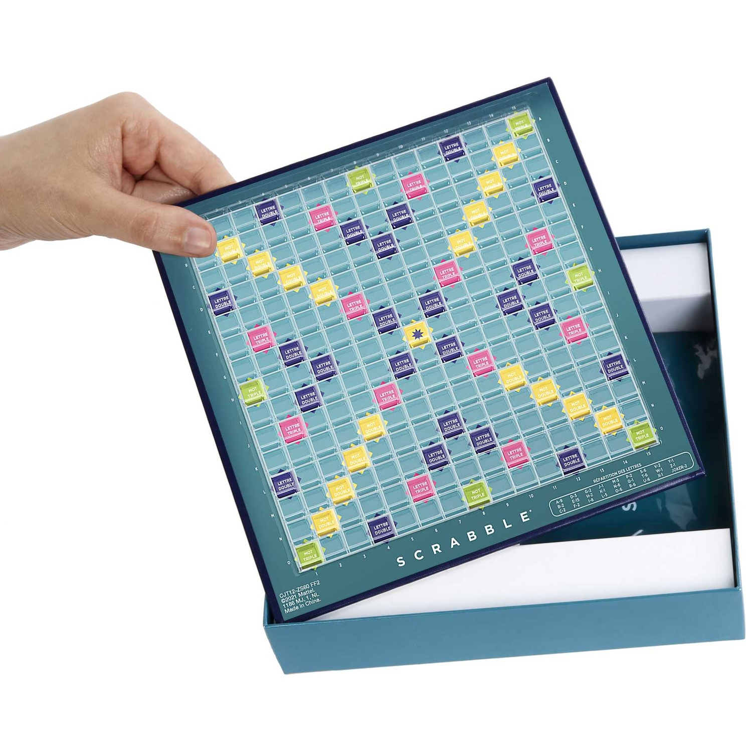 A hand lifts a blue Scrabble board above its open teal box against a white background.