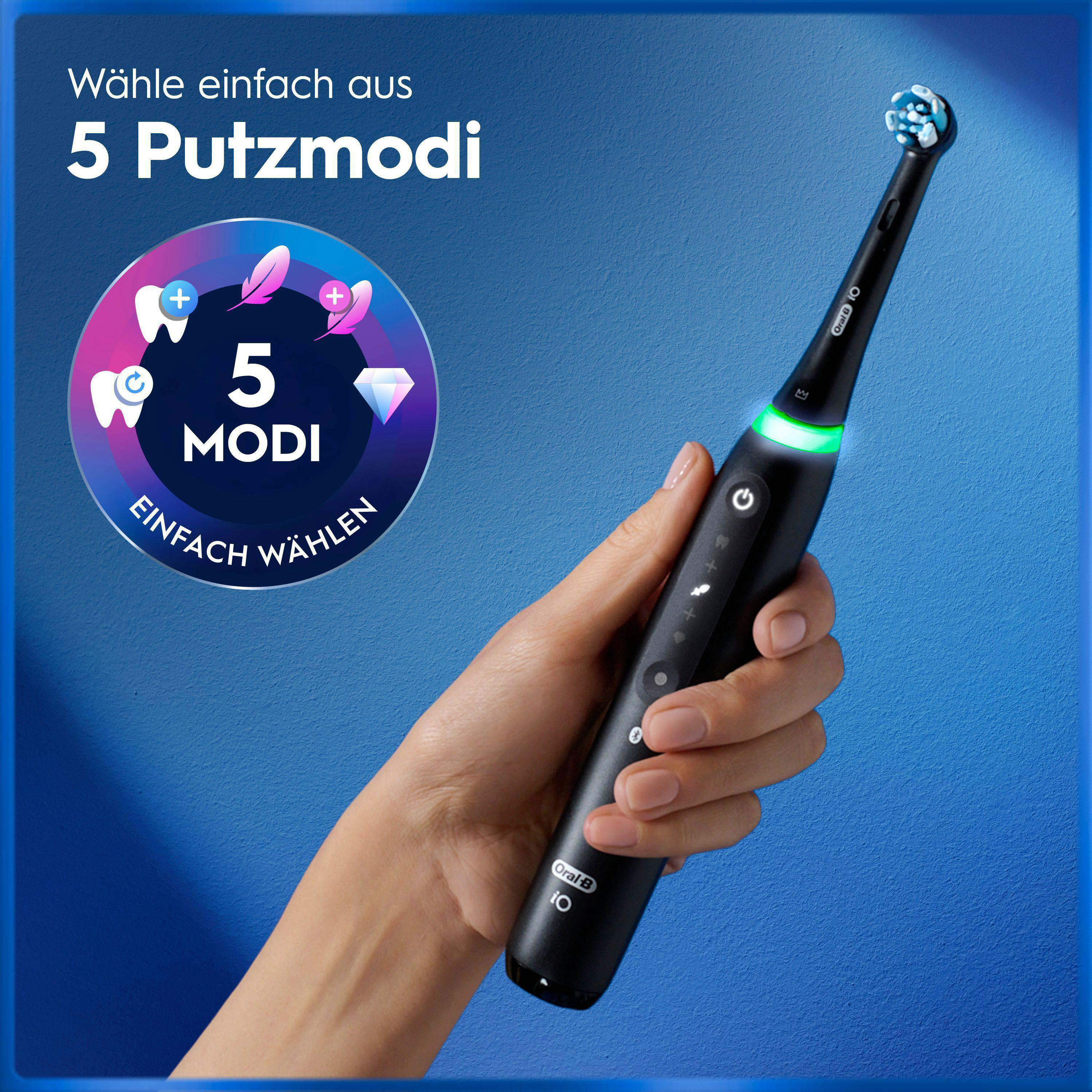Eine Hand hält eine schwarze Oral-B iO elektrische Zahnbürste mit grünem Licht vor blauem Hintergrund.