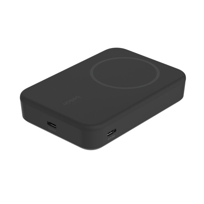 Un banco de energía inalambrico negro con puertos USB-C sobre una superficie blanca.