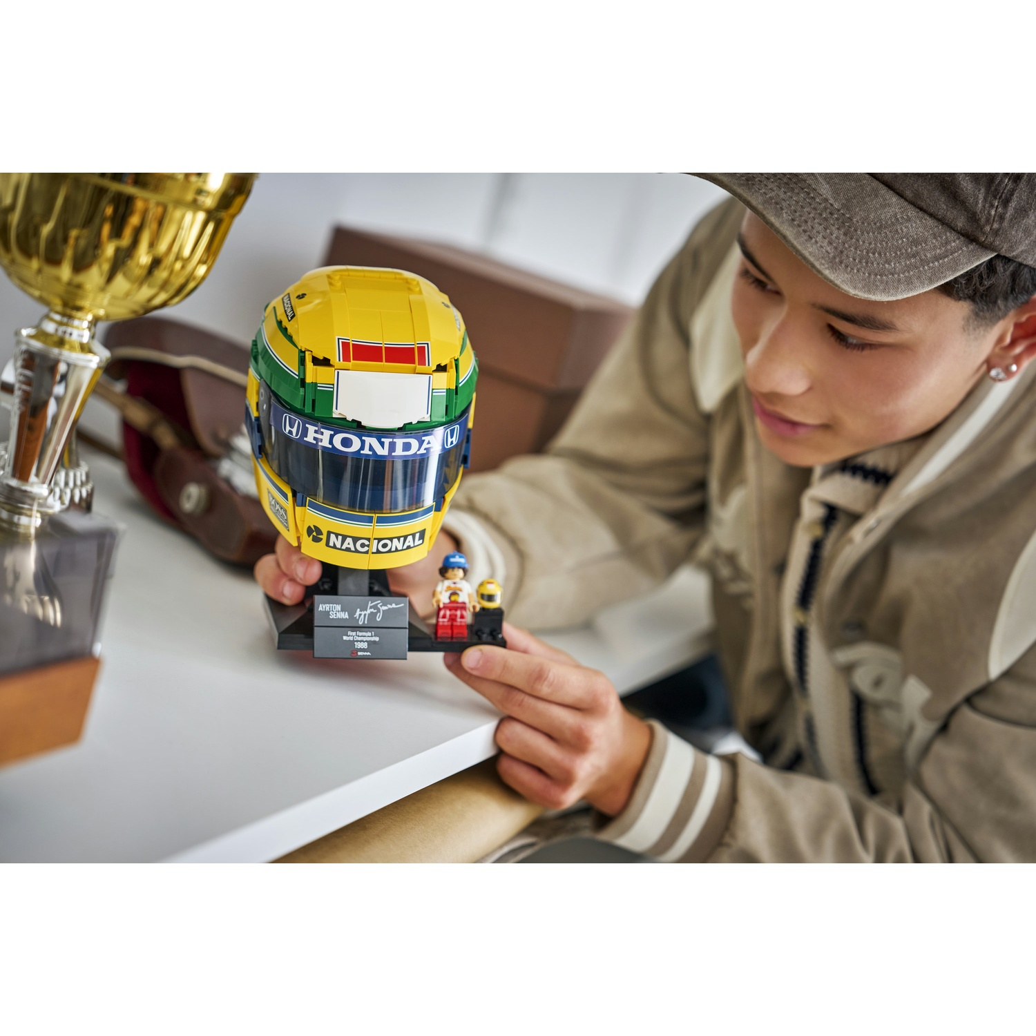 Un giovane con un berretto tiene in mano un modello di casco da corsa Lego di Ayrton Senna.