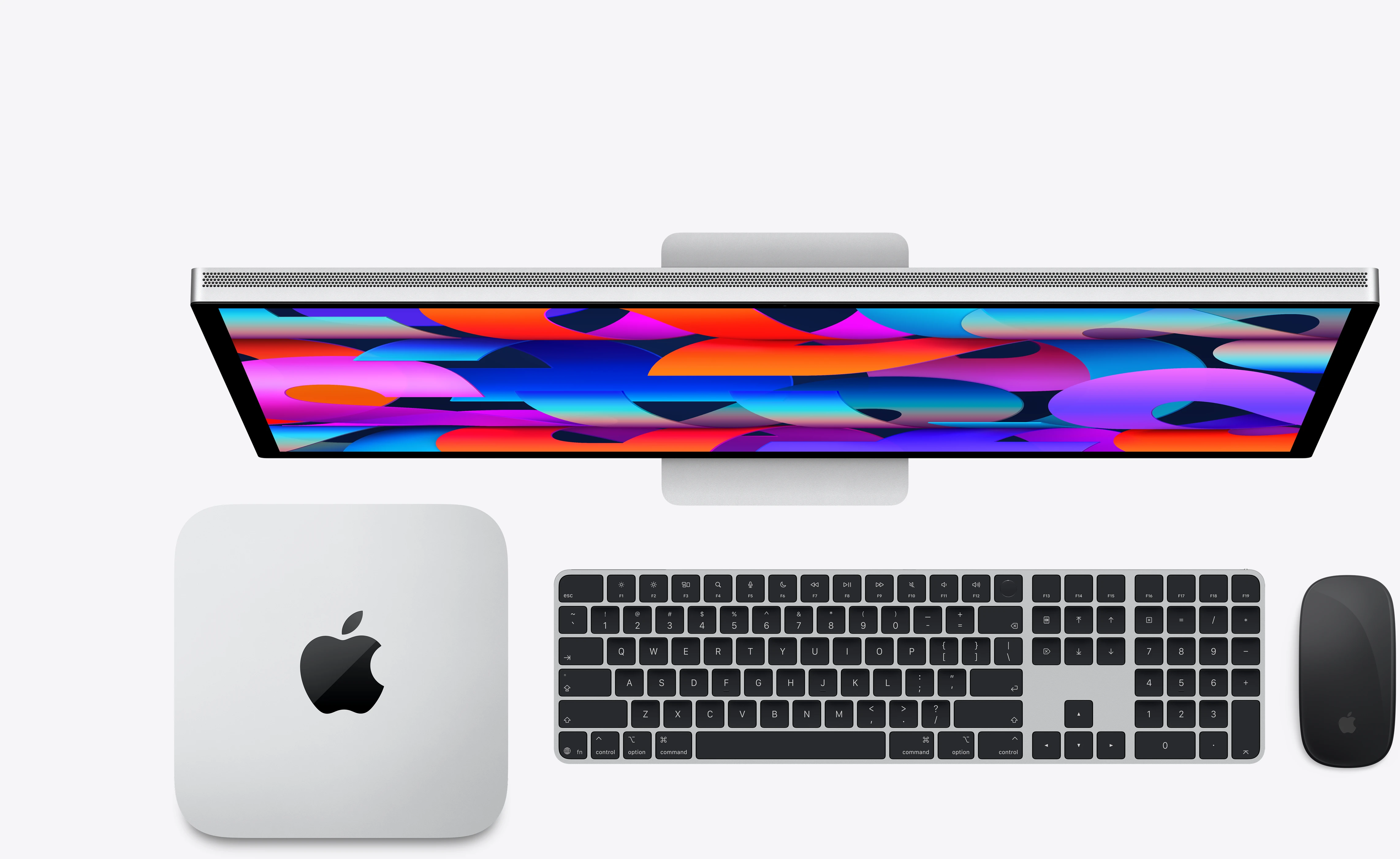 Felülnézetben egy Apple Mac mini billentyűzettel, egérrel és színes hátterű monitorral.