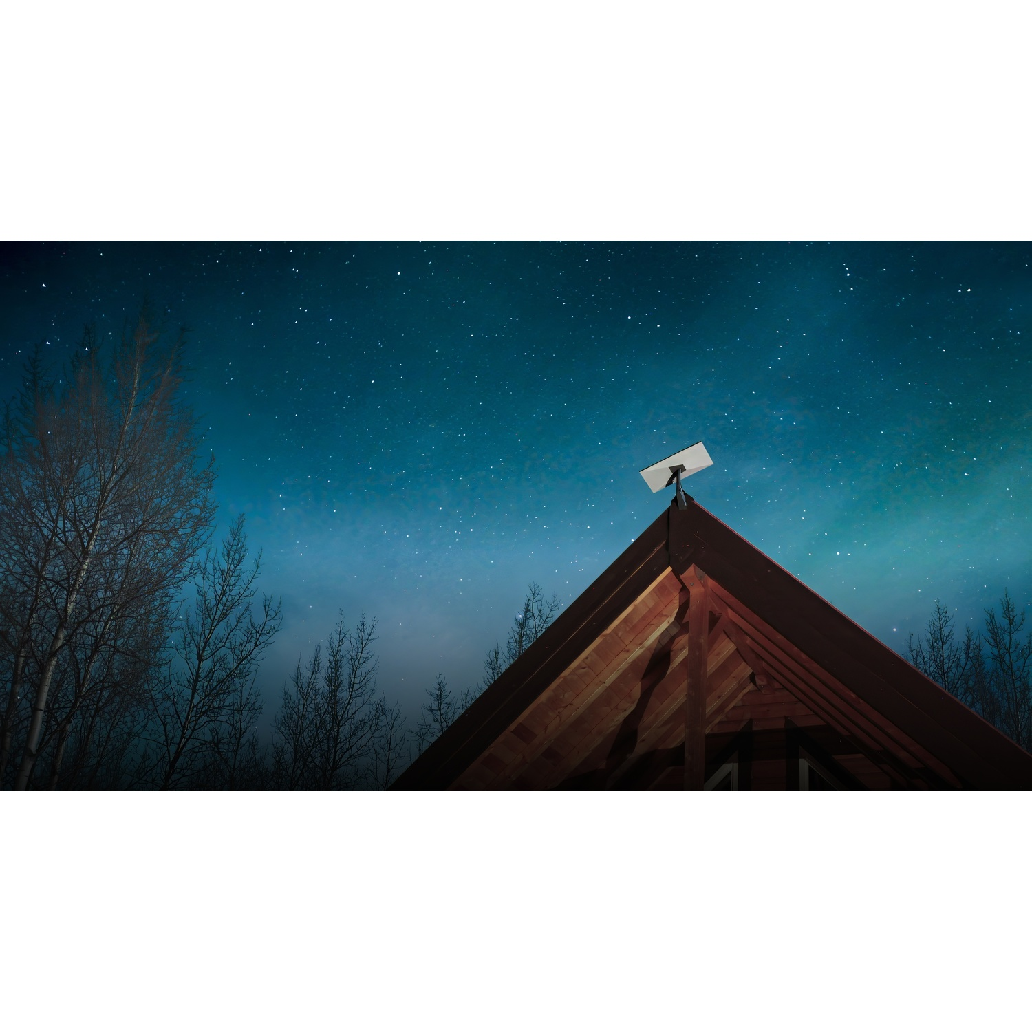 Una parabola su un tetto di legno contro un cielo notturno stellato e alberi.