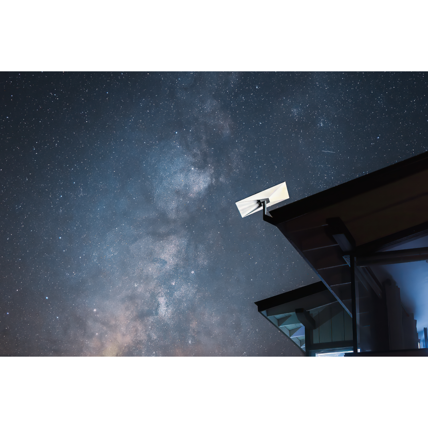 Una parabola su un tetto contro un cielo notturno stellato con la Via Lattea.