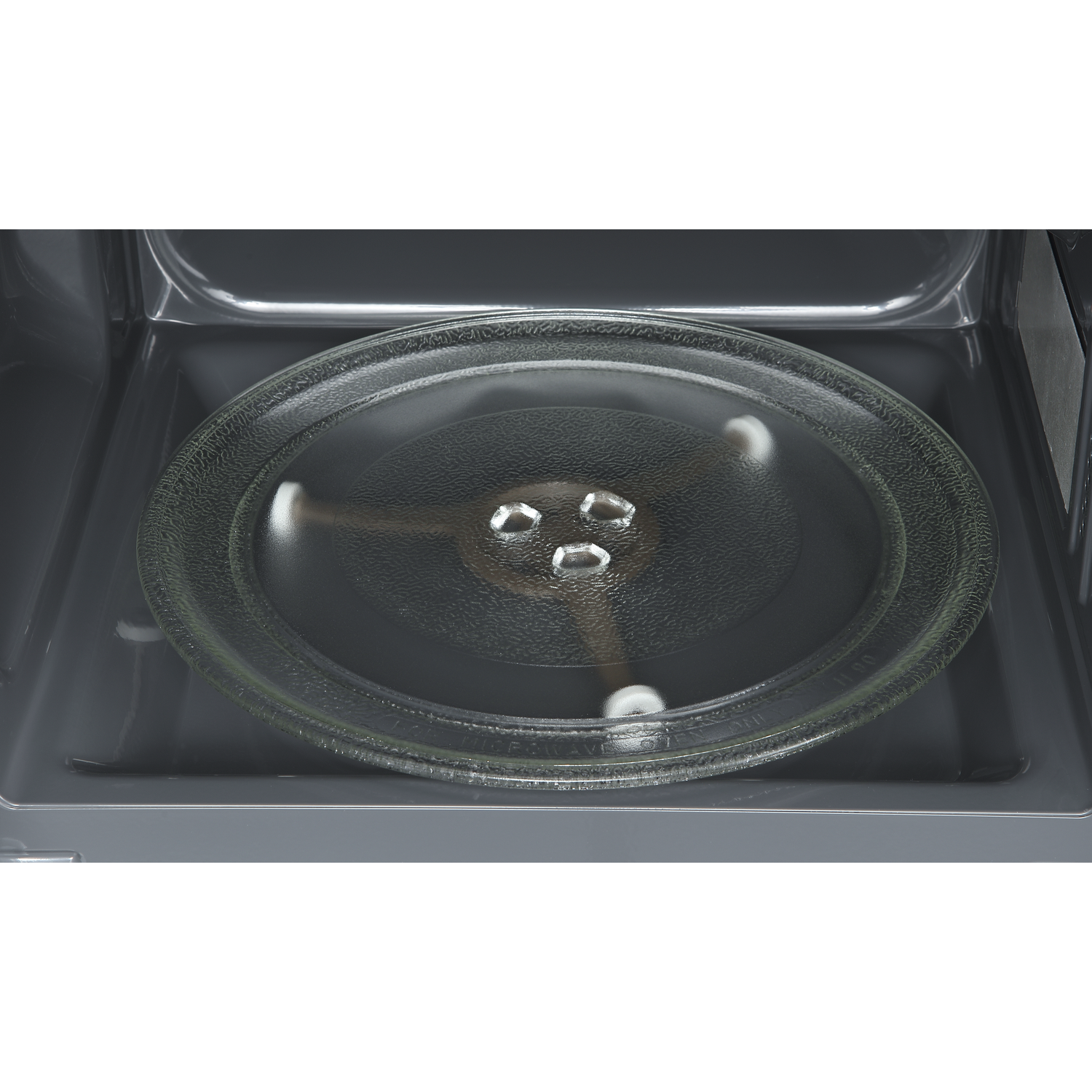 A glass turntable plate inside a dark microwave oven interior.