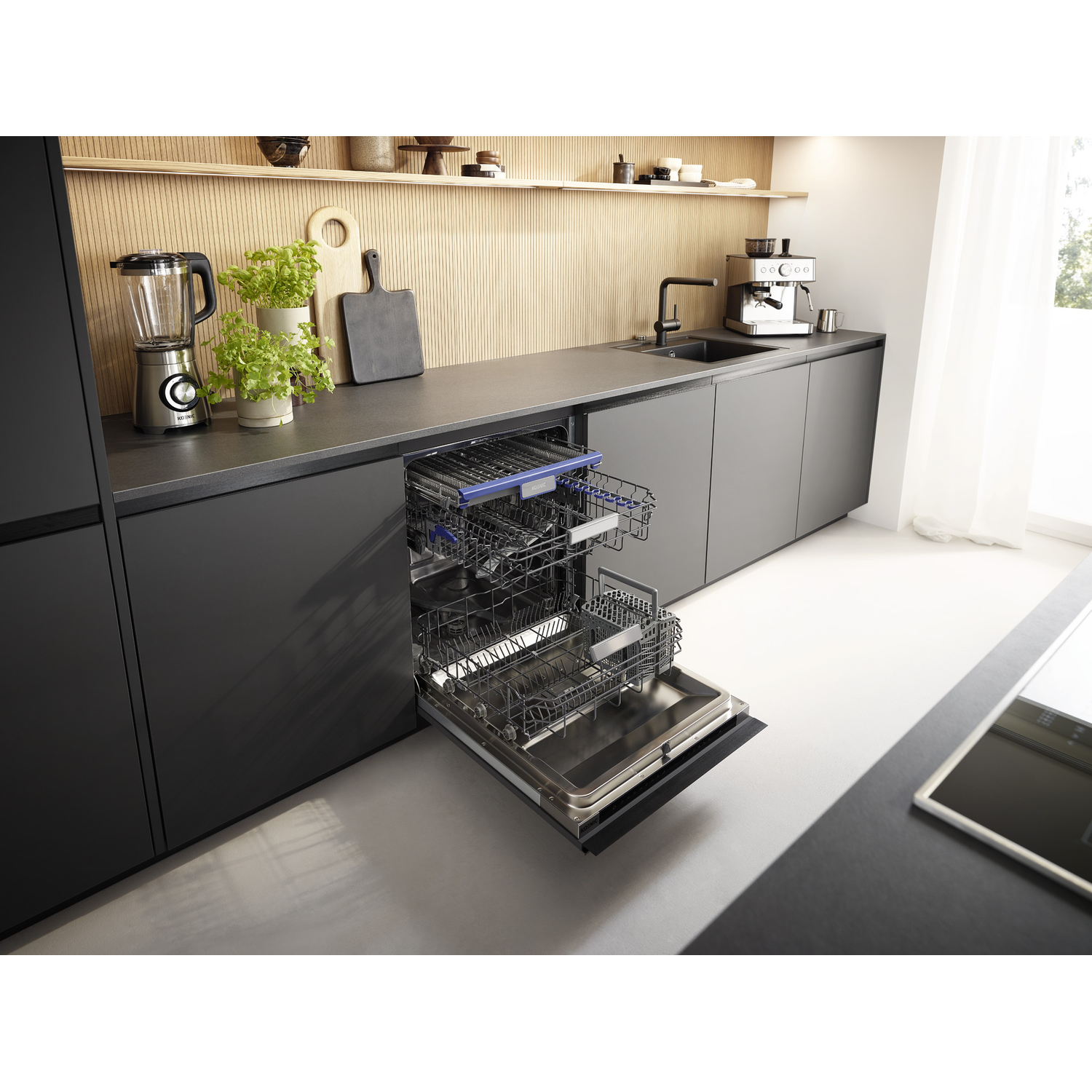 Modern kitchen with an open dishwasher in the center, dark cabinets, and appliances on the dark countertop.