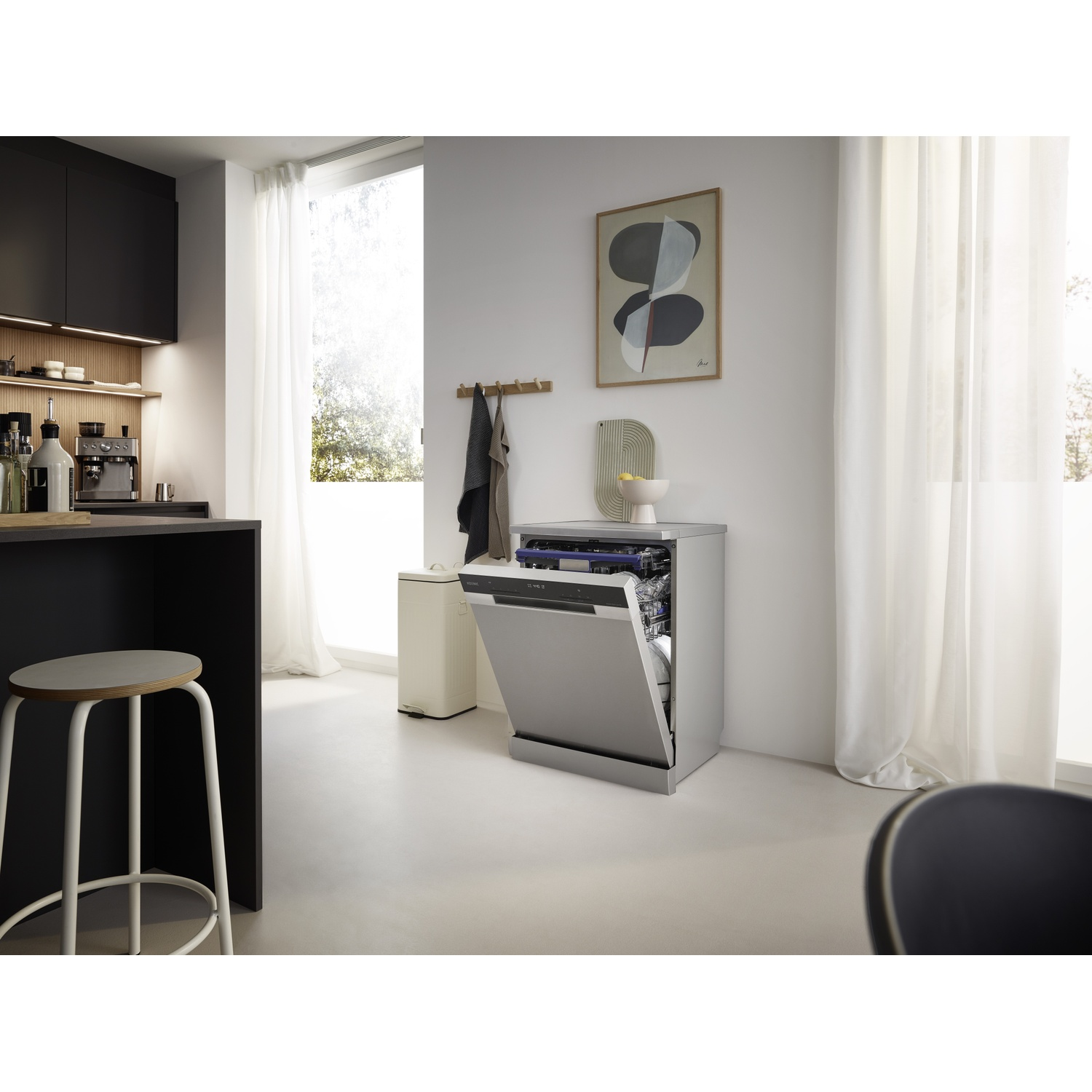 Modern kitchen featuring a silver dishwasher, framed wall art, and a bar stool in the foreground.