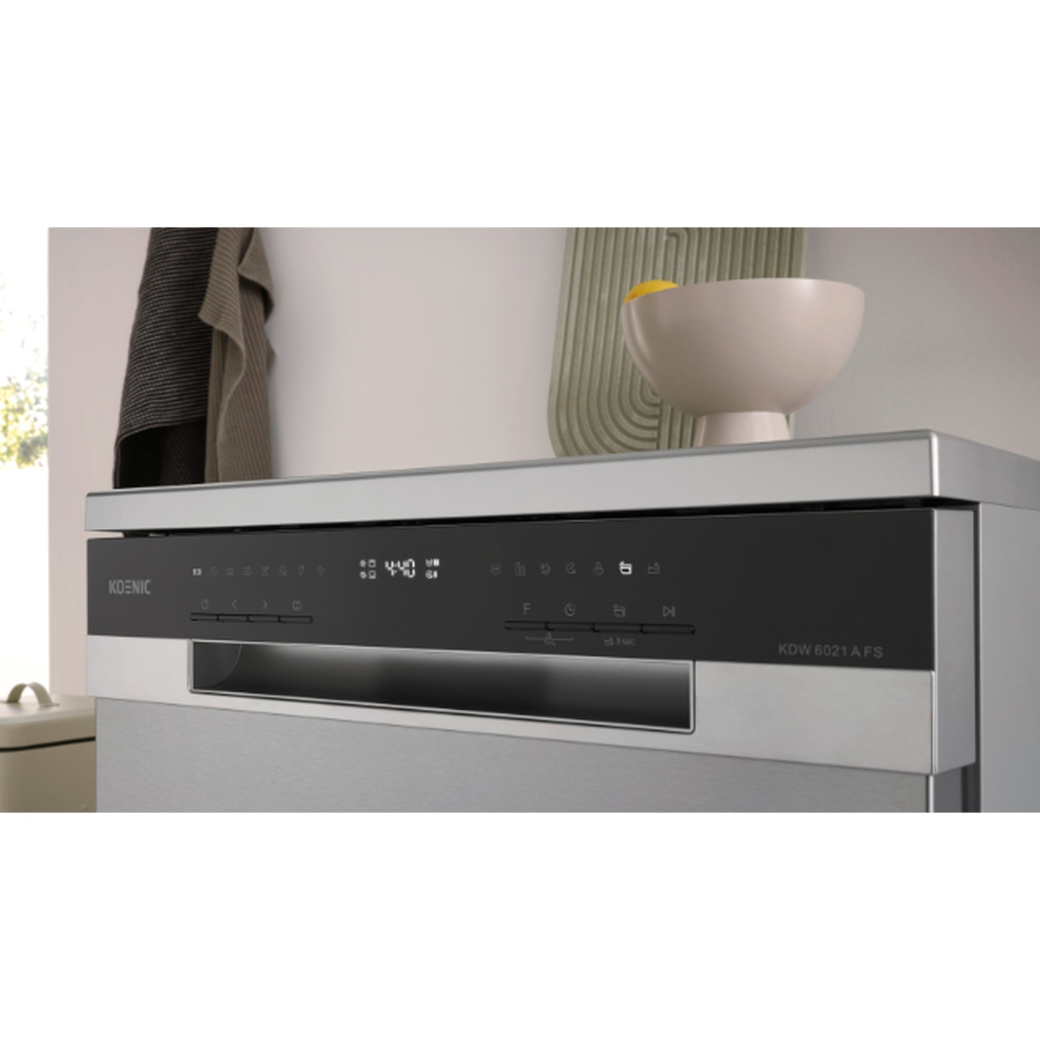A silver Koenic dishwasher control panel is visible, with touch buttons, a digital display, and a bowl on top.