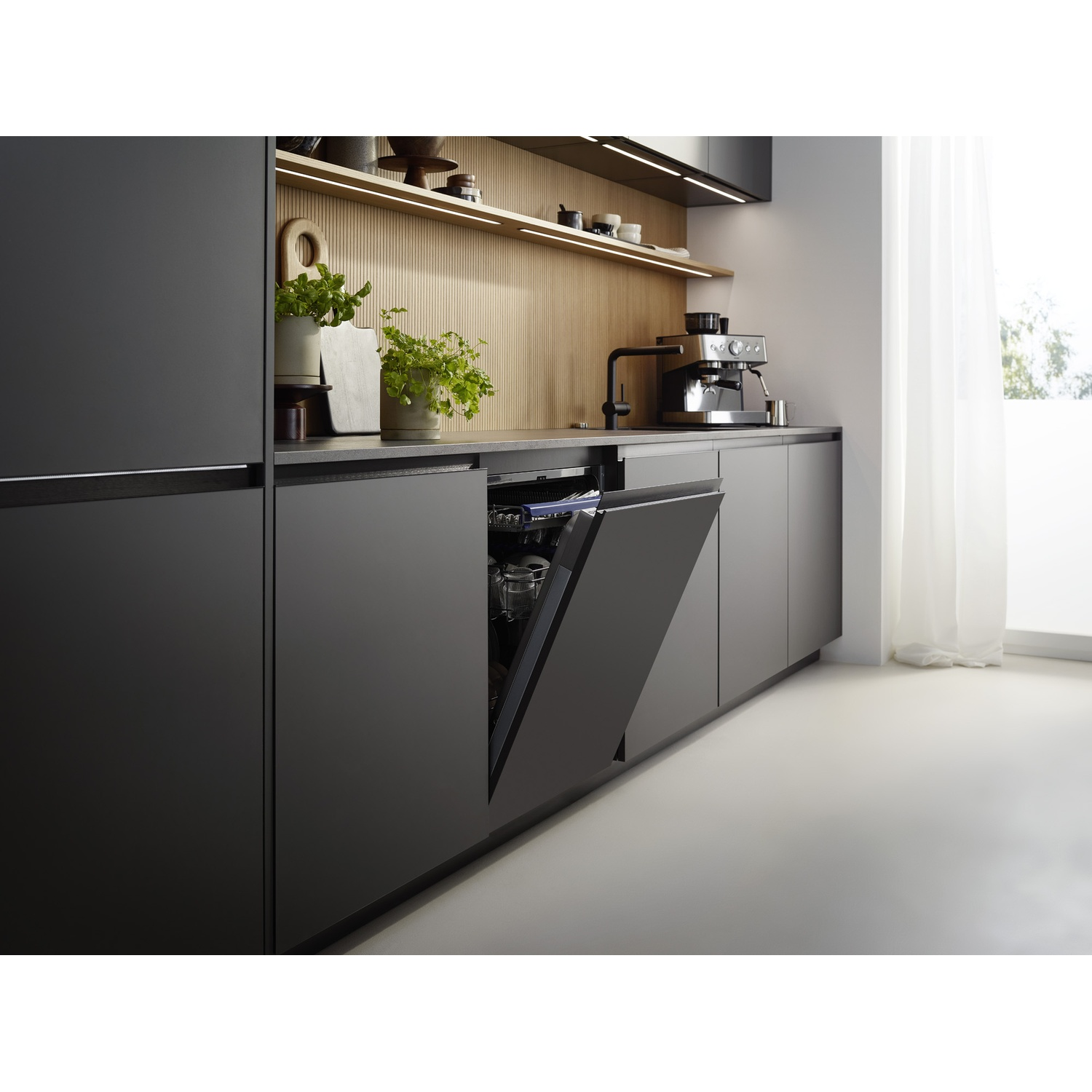 Modern dark kitchen with an open dishwasher, wooden backsplash, coffee machine, and shelves.