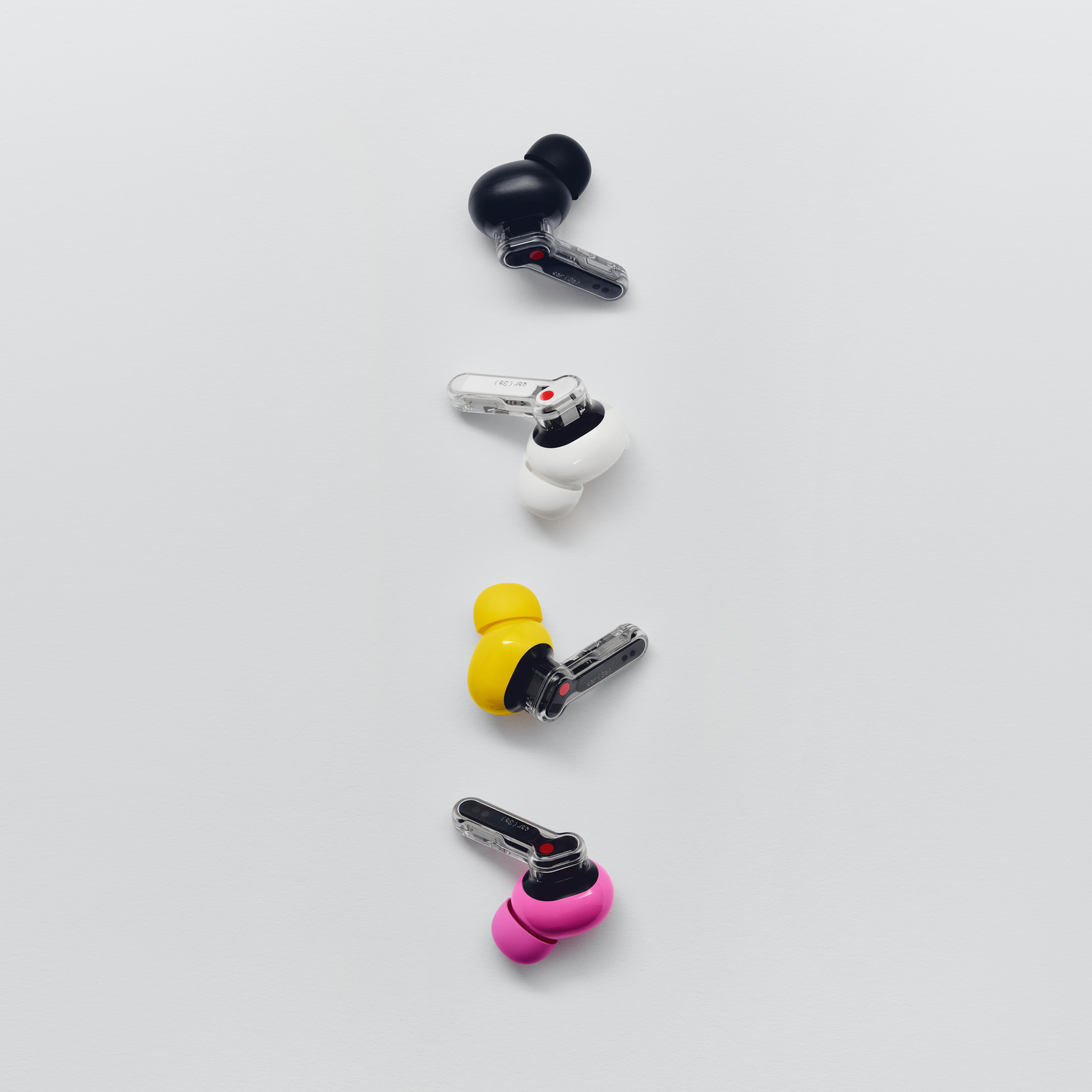 Vier drahtlose In-Ear-Kopfhörer in Schwarz, Weiß, Gelb und Pink mit transparenten Stielen auf hellem Hintergrund.