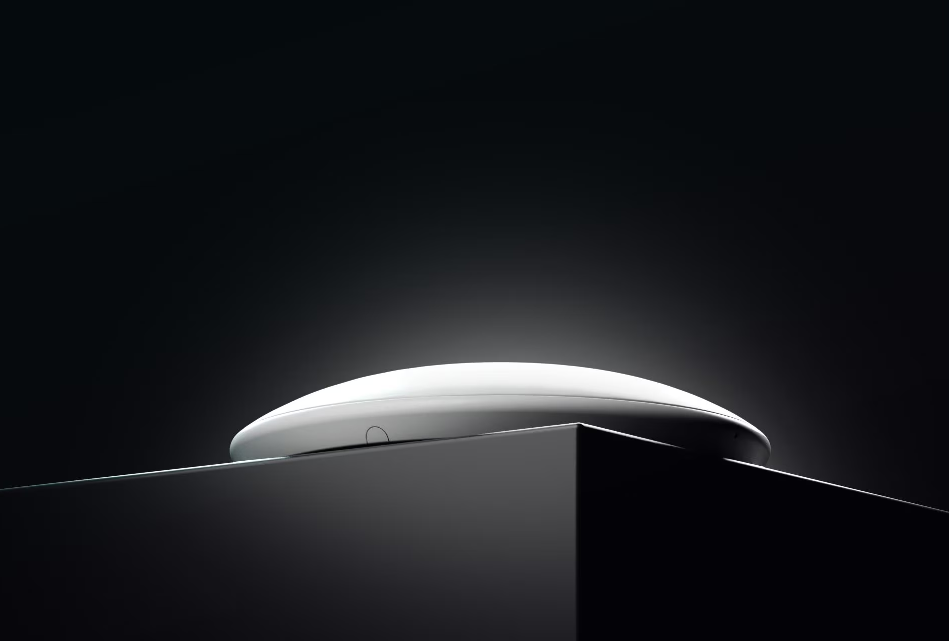Un oggetto bianco a forma di disco si trova su una superficie scura su sfondo nero.