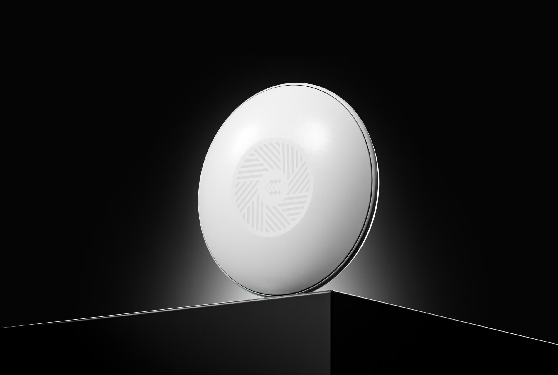 Un dispositivo rotondo bianco con un motivo centrale su un piedistallo scuro su sfondo nero.