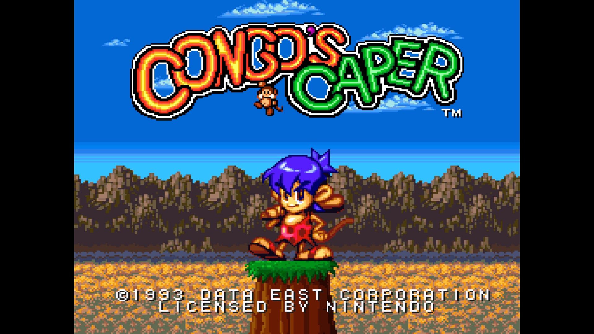 Pantalla de título del videojuego Congo's Caper con un pequeño personaje de mono sobre un tronco ante montañas.