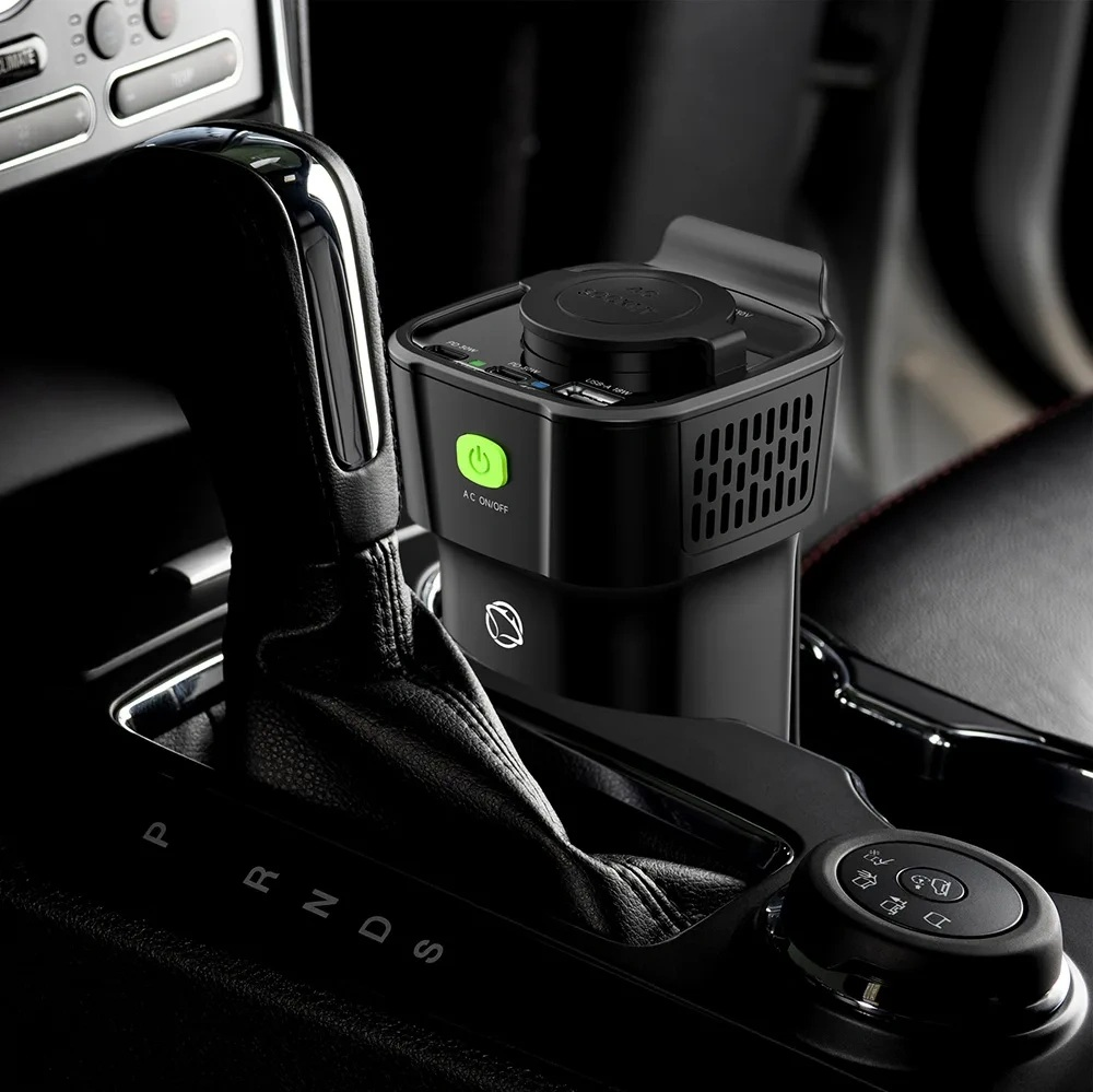 Czarny falownik samochodowy z jasnozielonym przyciskiem zasilania znajduje się w uchwycie na kubek.