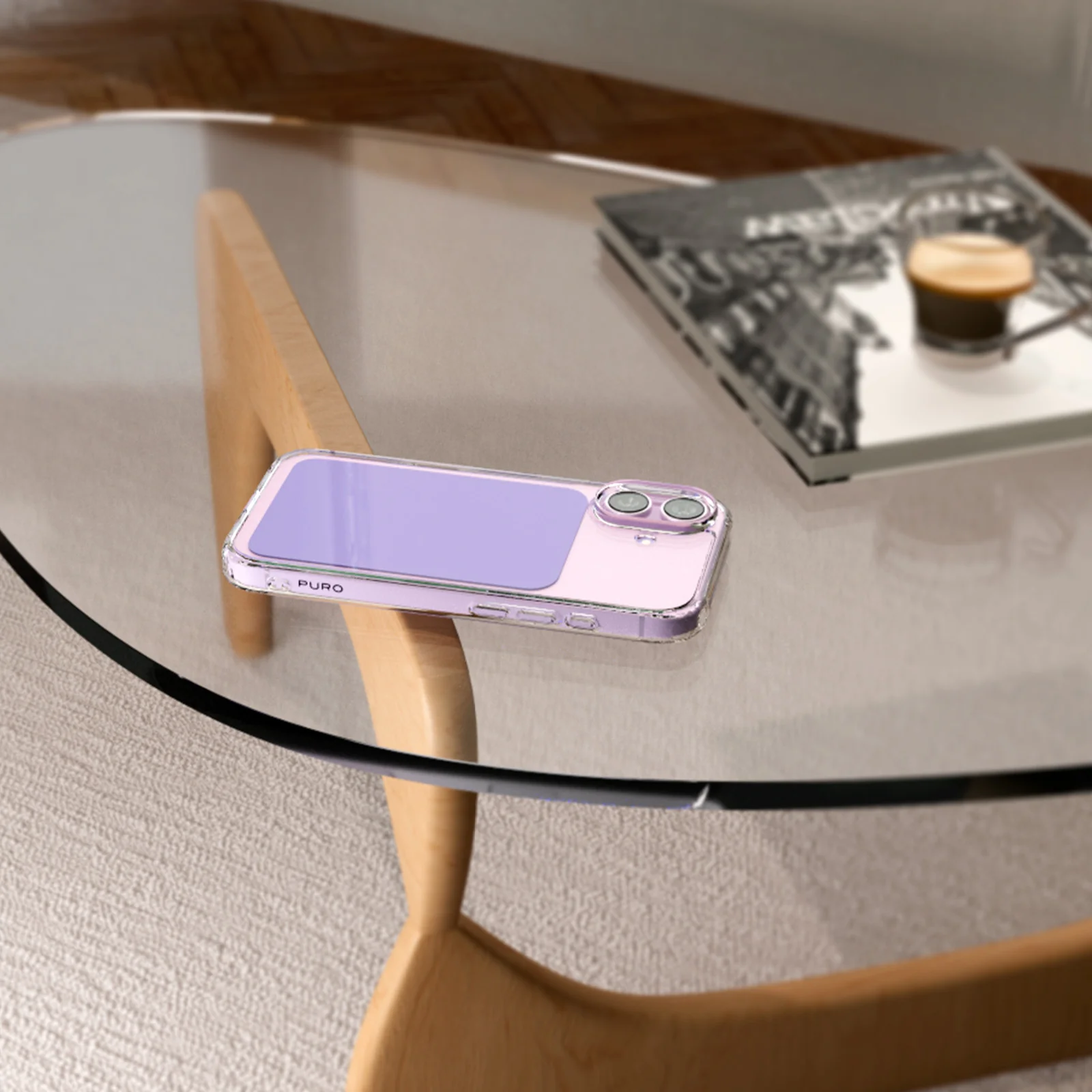 Ein lilafarbenes Smartphone in transparenter Hülle liegt auf einem Glastisch neben einer Zeitschrift und einer Tasse Kaffee.