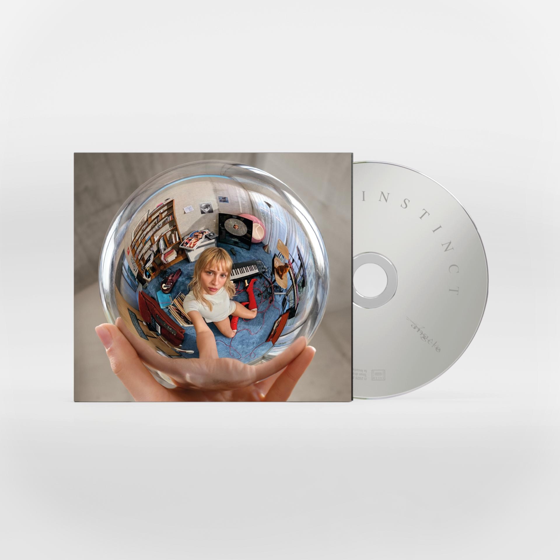 Hand hält glänzende Kugel mit Raumspiegelung; daneben silberne CD mit der Aufschrift INSTINCT.