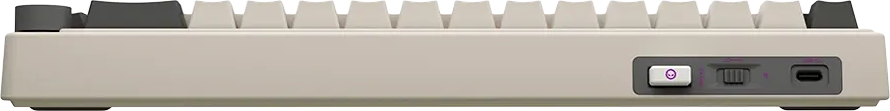 Egy bézs színű billentyűzet oldalnézete kapcsolóval, csúszkával és USB-C porttal.