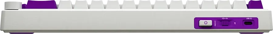 Egy fehér billentyűzet hátoldala lila részletekkel, egy kapcsolóval, üzemmód-választóval és USB-C porttal.