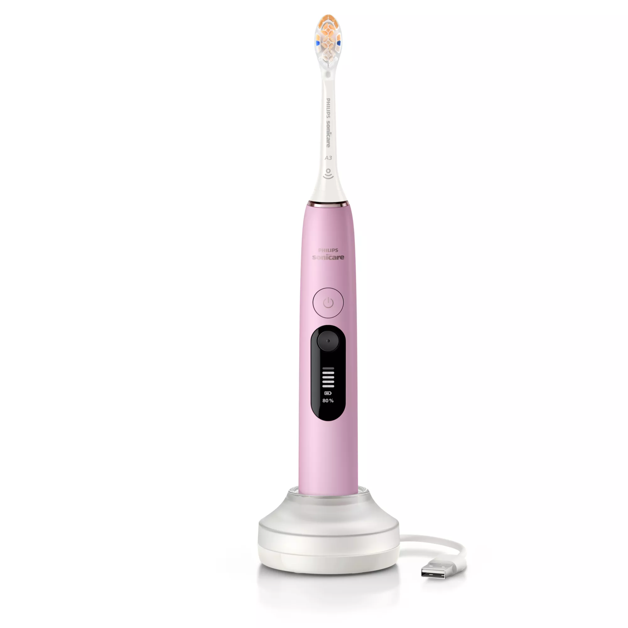 Egy rózsaszín Philips Sonicare elektromos fogkefe fehér töltőalapon, USB kábellel, fehér háttér előtt.