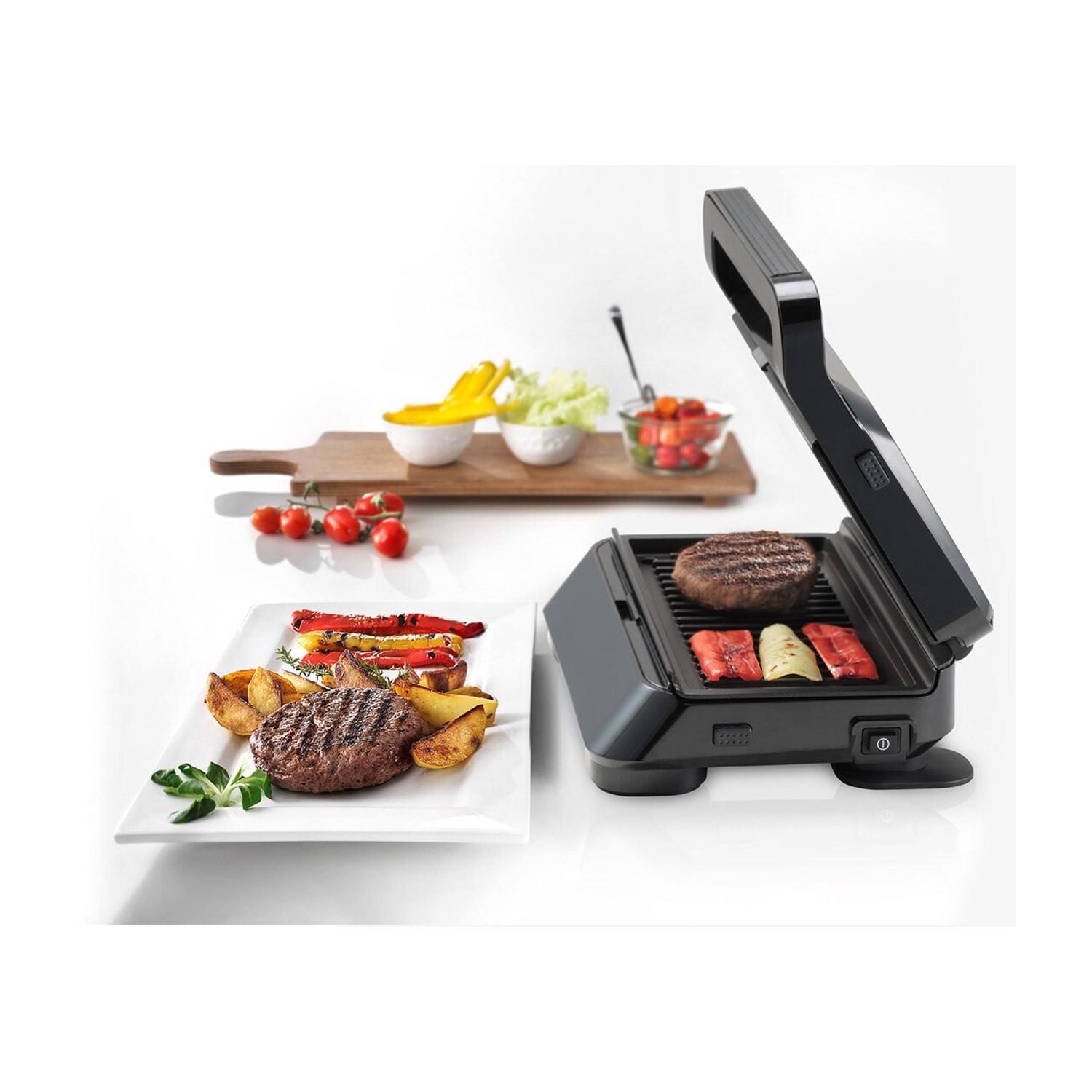 Una grill elettrica con hamburger e peperoni, accanto a un piatto bianco e un tagliere.