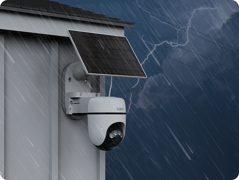 Una cámara de seguridad con un panel solar está montada en una pared blanca durante una tormenta.
